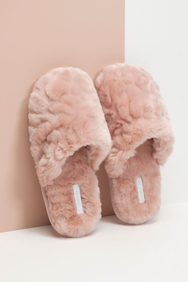 Предметная съемка тапочек на мягкой поверхности, подчеркивающая уют и комфорт