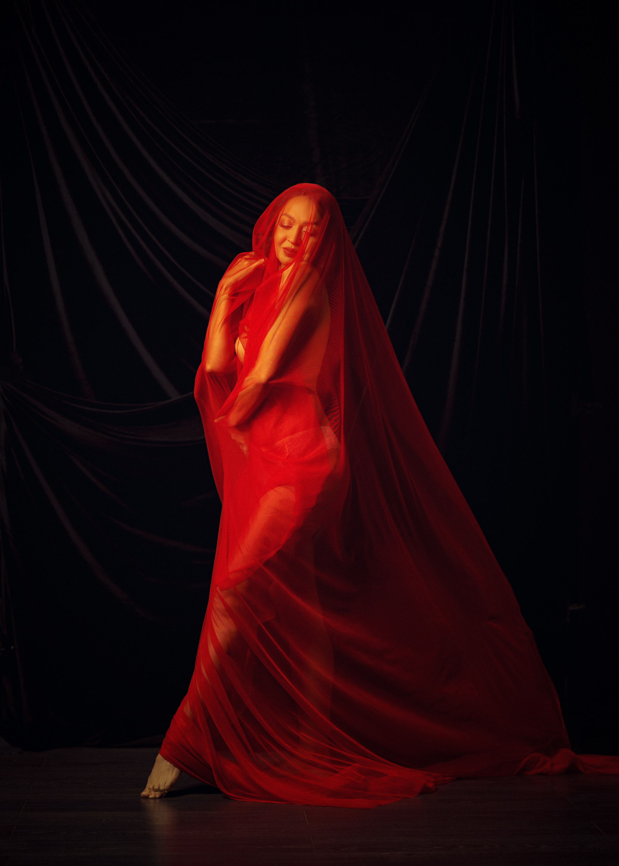 Будуар и ню фотография — красная ткань, тени и глубокий чёрный фон