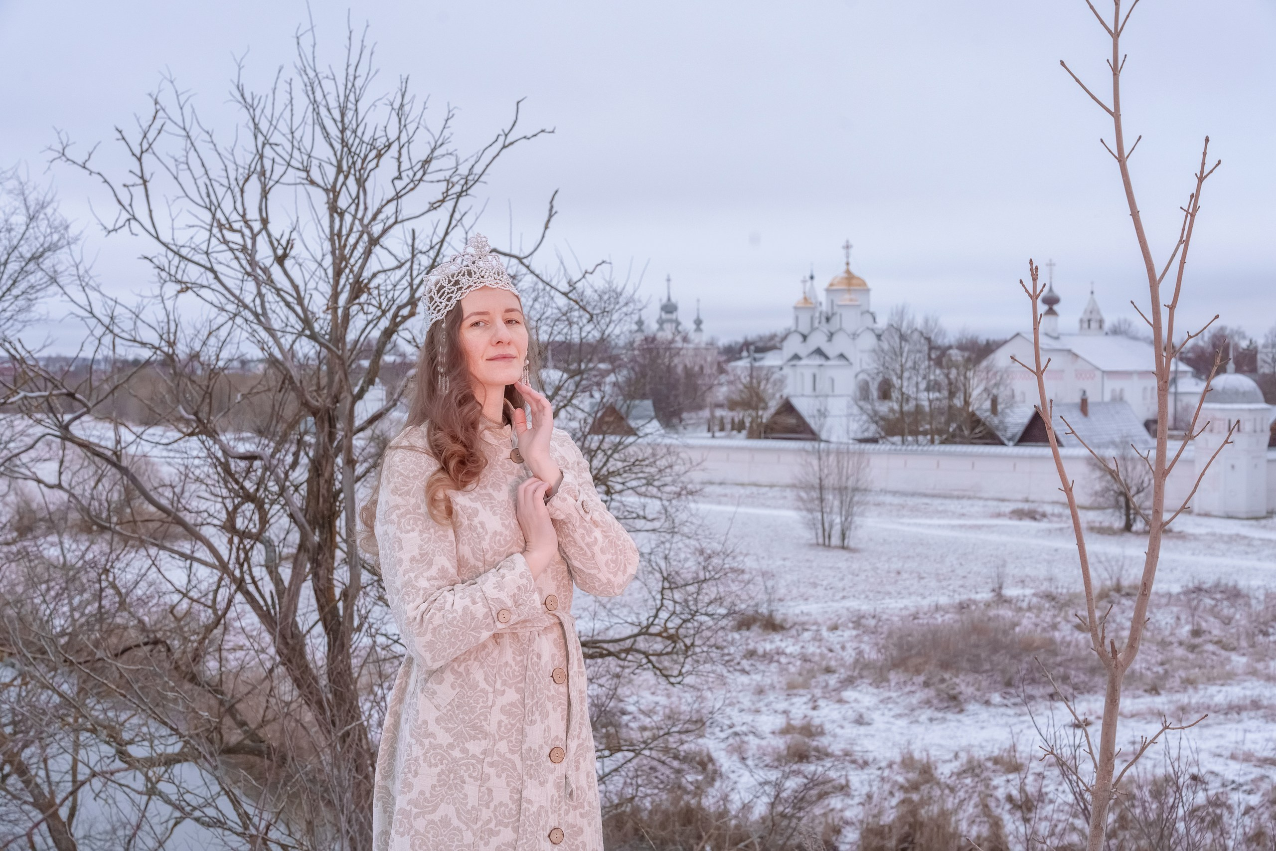 A girl in a russian costume on the background of a temple in Suzdal by the river