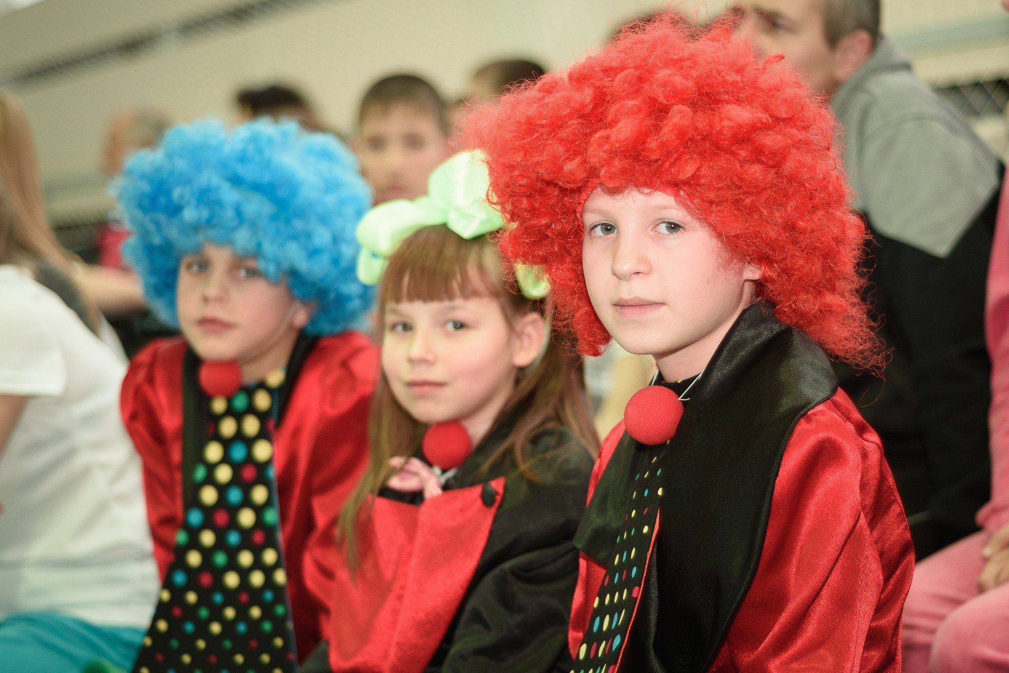 Дети в клоунских костюмах и цветных париках смотрят в камеру