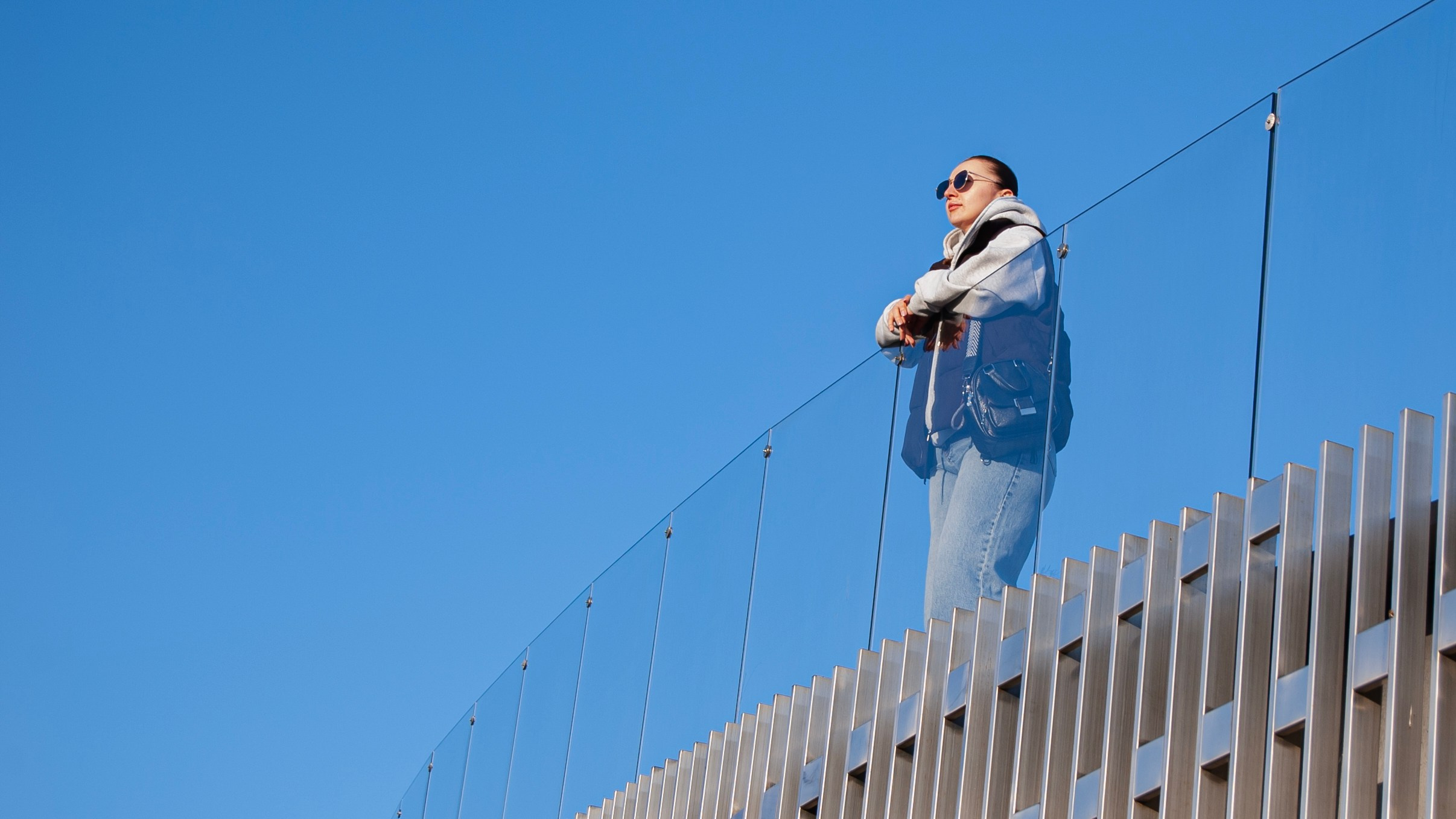 Девушка облокотилась на парапет и смотрит на закат