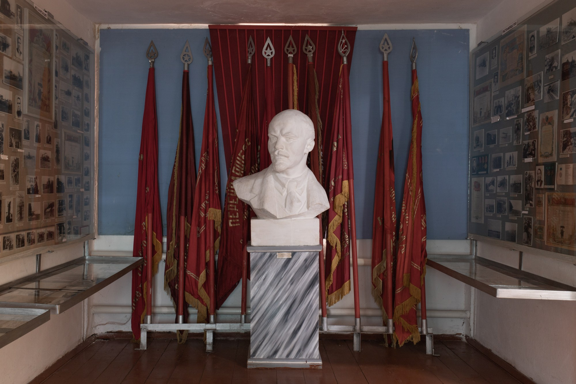 Ленин и советские знамёна в зале народного музея села. Экспонаты здесь собраны от местных жителей, которые передавали уникальные вещи, когда-то присланные в коммуну со всего мира.