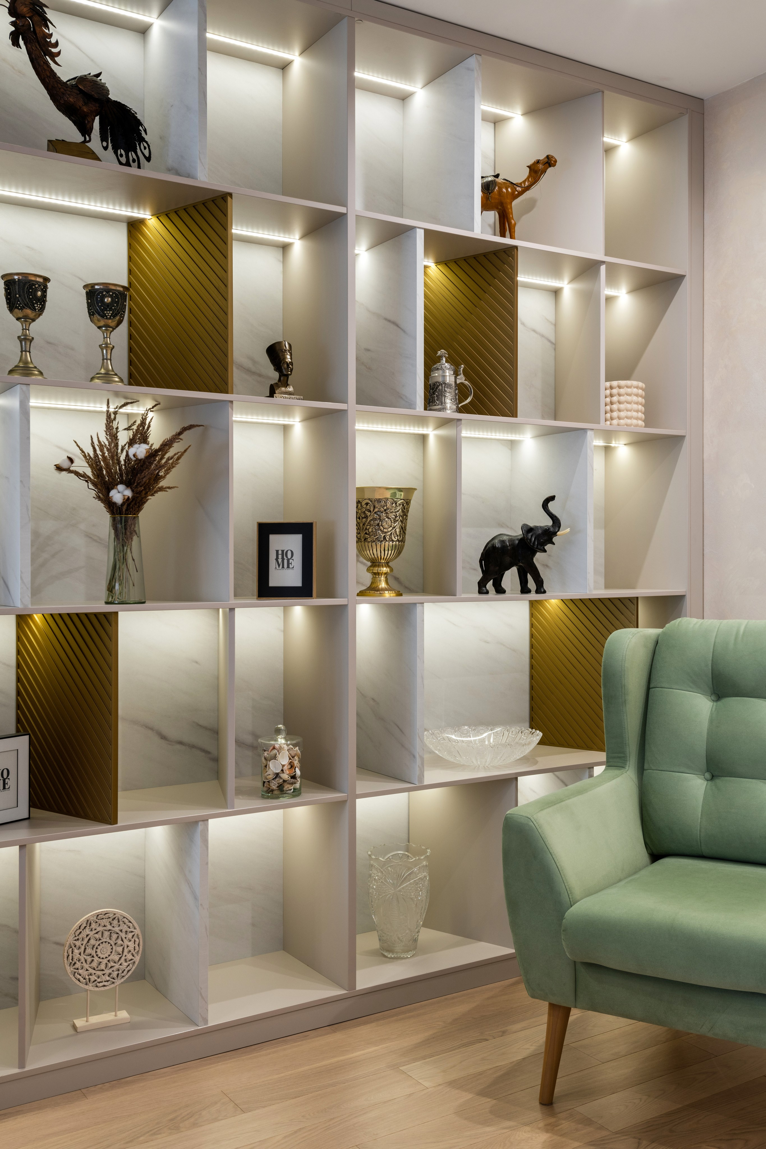 Современная гостиная со стеллажами и подсветкой, выделяющей серию декоративных предметов и скульптур.