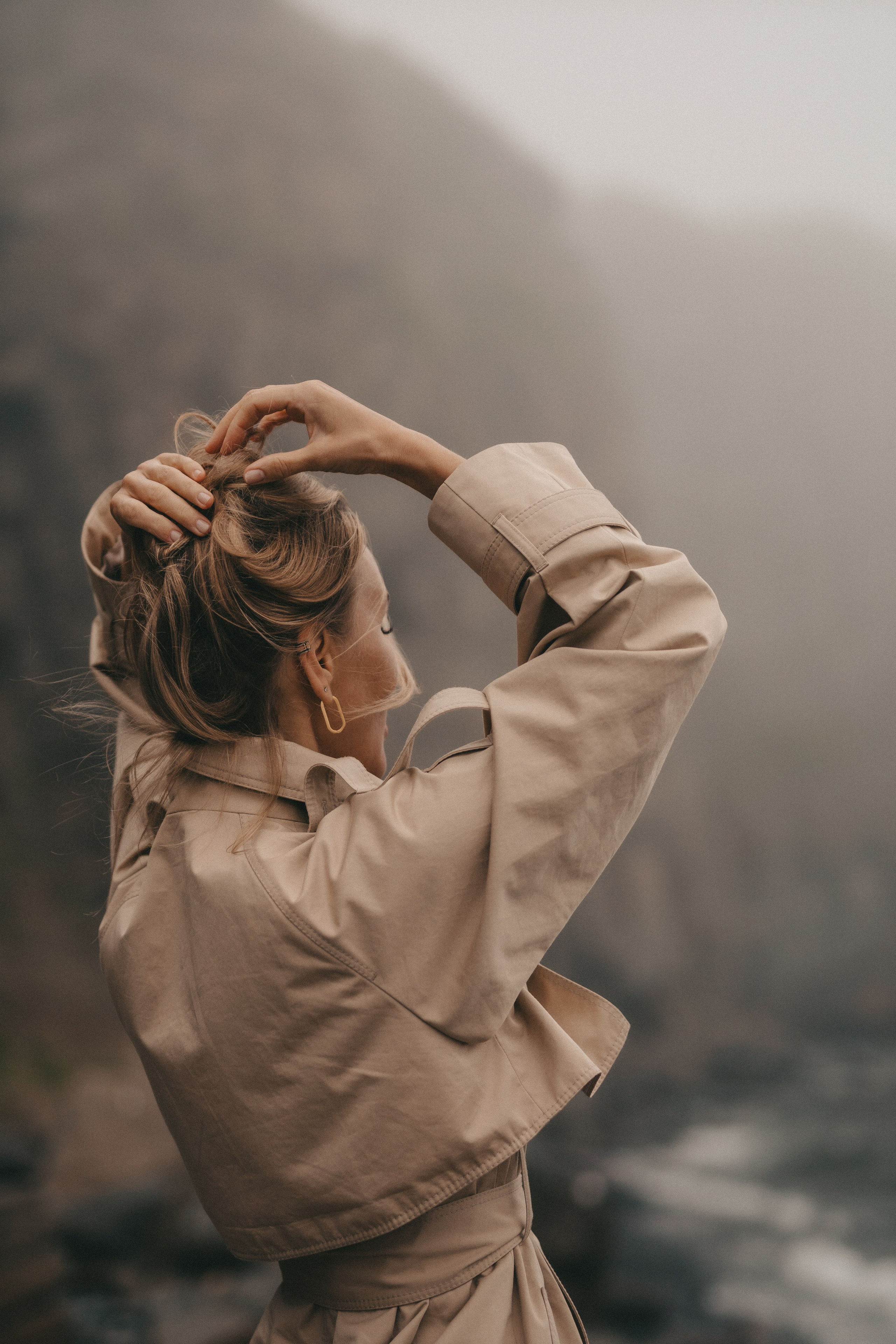 девушка со спины смотрит на море в тумане трогает волосы