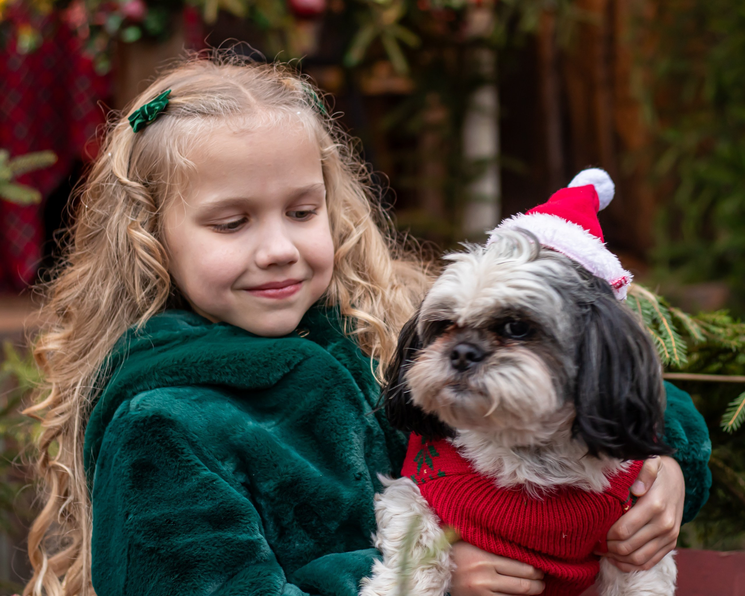 Девочка улыбается, сидя среди еловых веток и подарков, новогодняя фотосессия, фотограф Карасёва Елена
