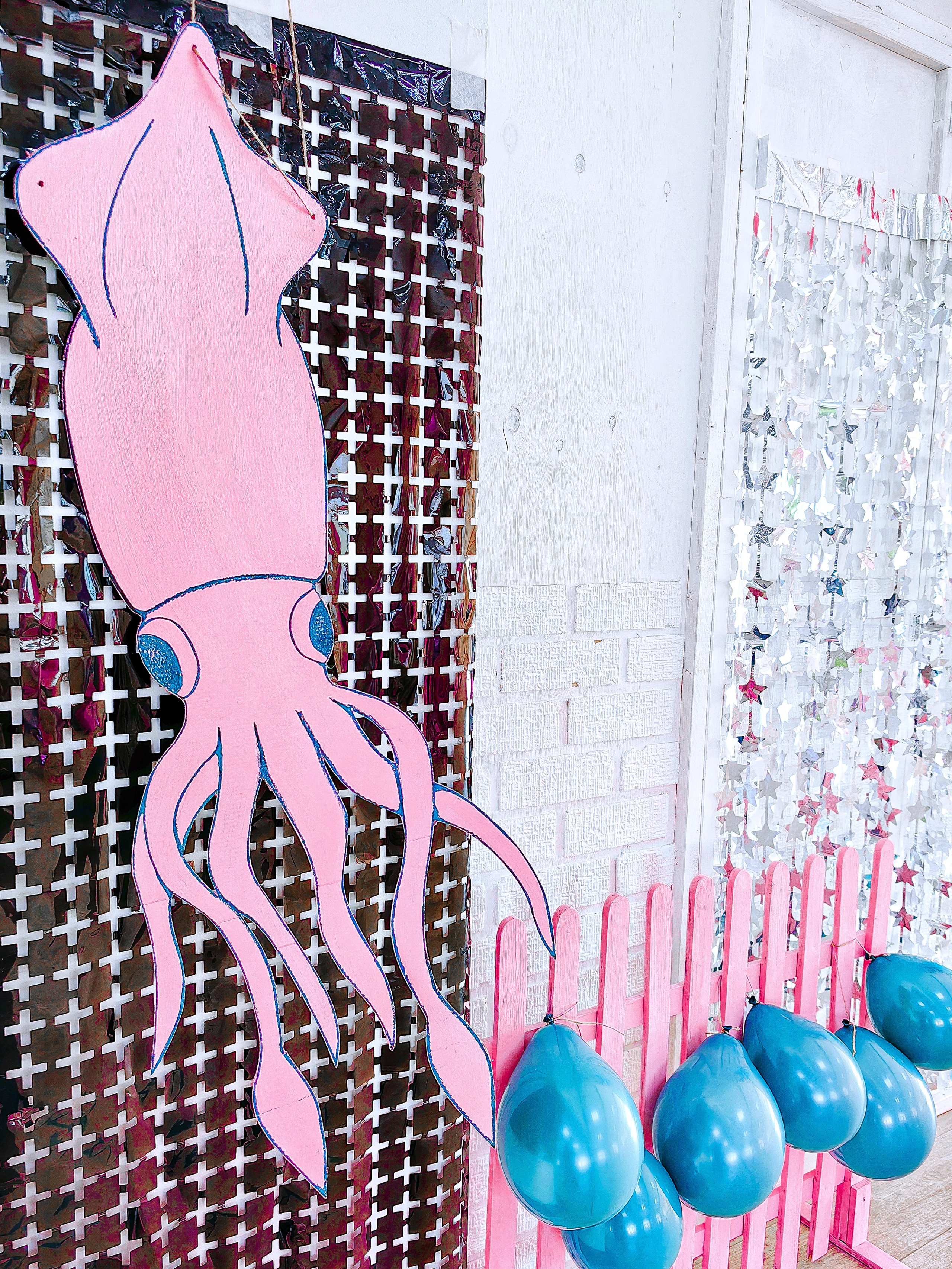 Розовая фигура кальмара на черном голографическом фоне - как оформление и декорации к мероприятию в стиле Игры в кальмара