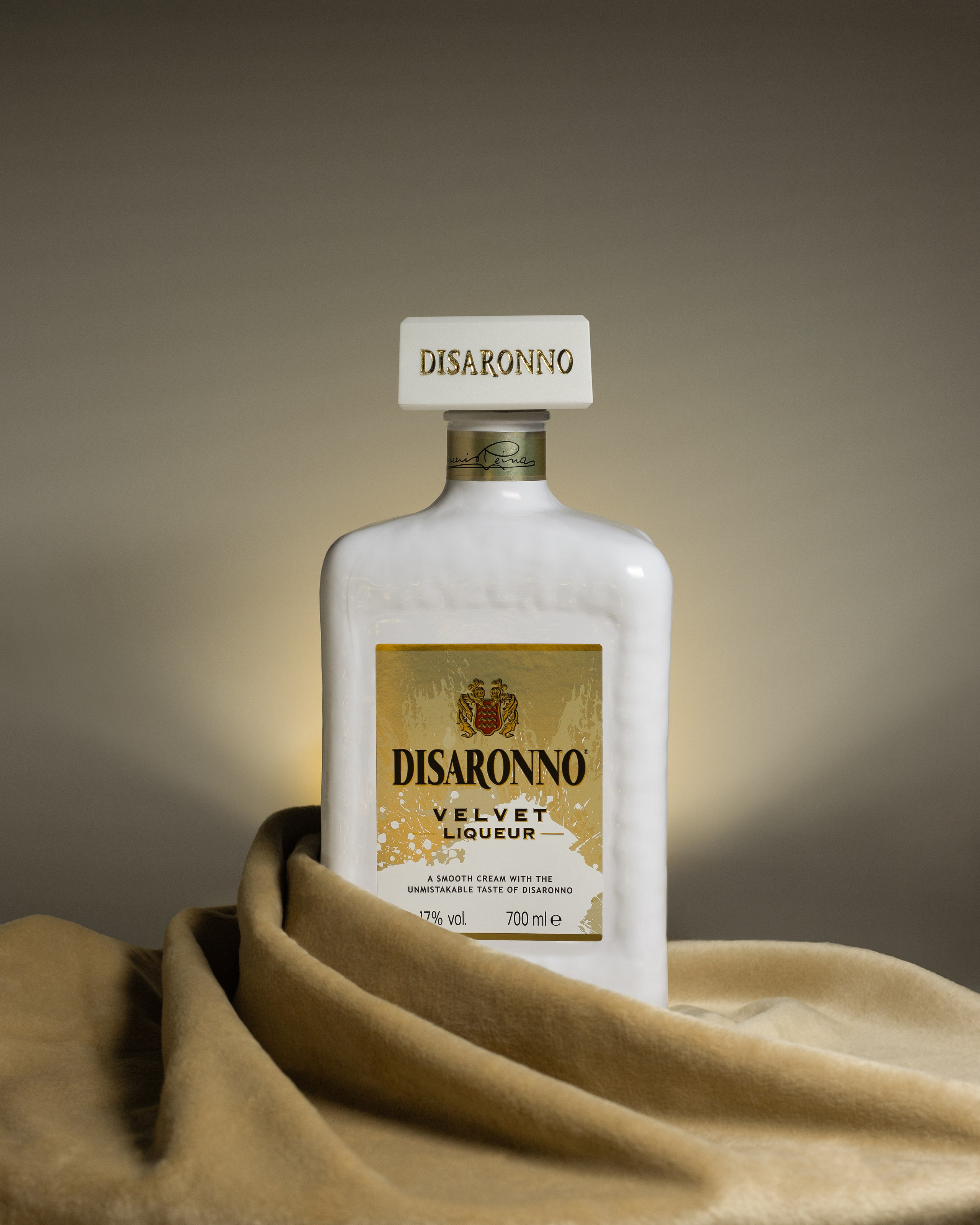 Итальянский сливочный ликер Disaronno Velvet с вельветовой бархатной тканью. Коммерческая фотография продукта.