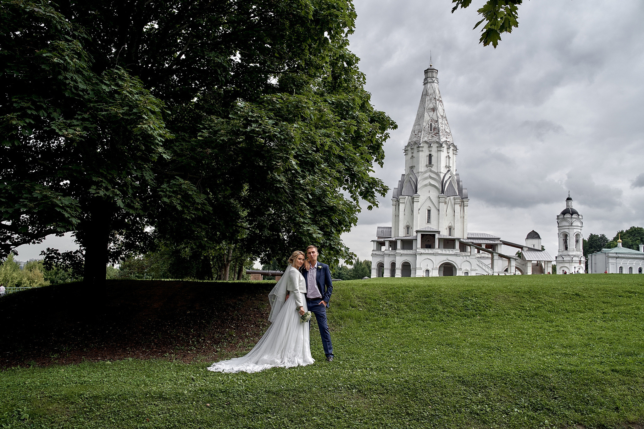 Жених и невеста идут по лужайке на фоне церкви  Свадебная фотосъемка в  Коломенском. Свадебный фотограф в Москве  Сергей Гаварос.