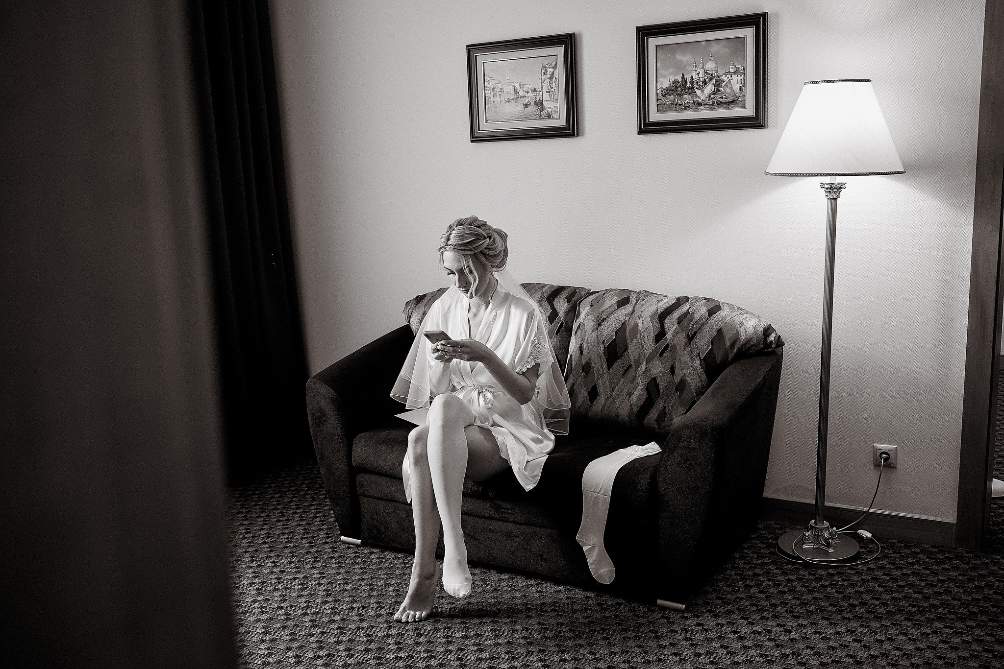 Невеста сидит на диване и смотрит в смартфон утро невесты Свадебная фотосъемка в  отеле Милан. Свадебный фотограф в Москве  Сергей Гаварос.