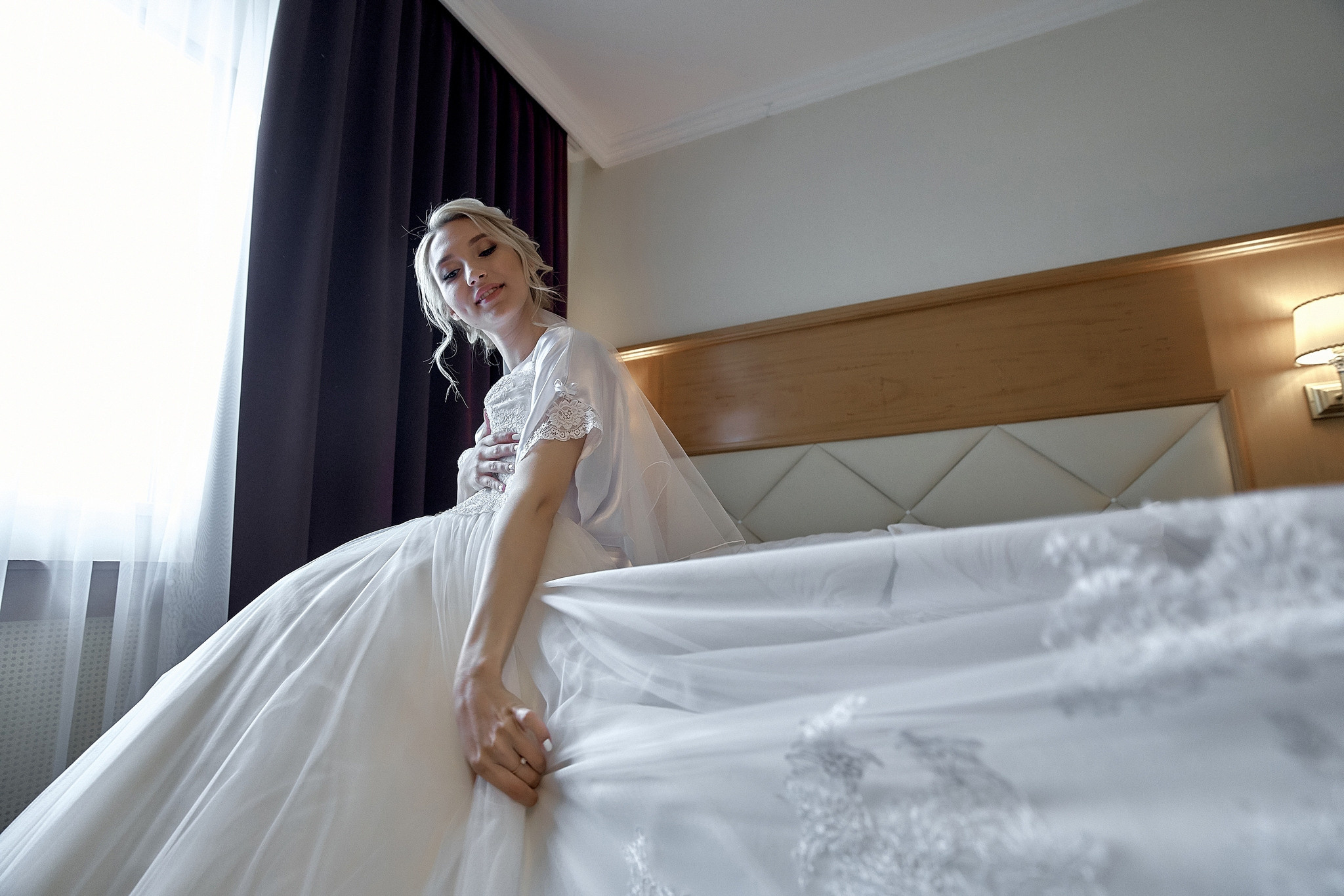 невеста сидит на краю кровати - съемка снизу. Свадебная фотосъемка в  отеле Милан. Свадебный фотограф в Москве  Сергей Гаварос.