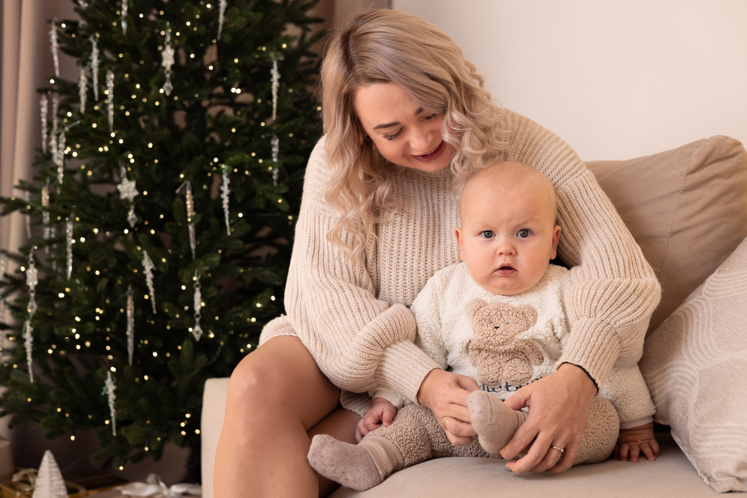 Мама обнимает малыша у елки