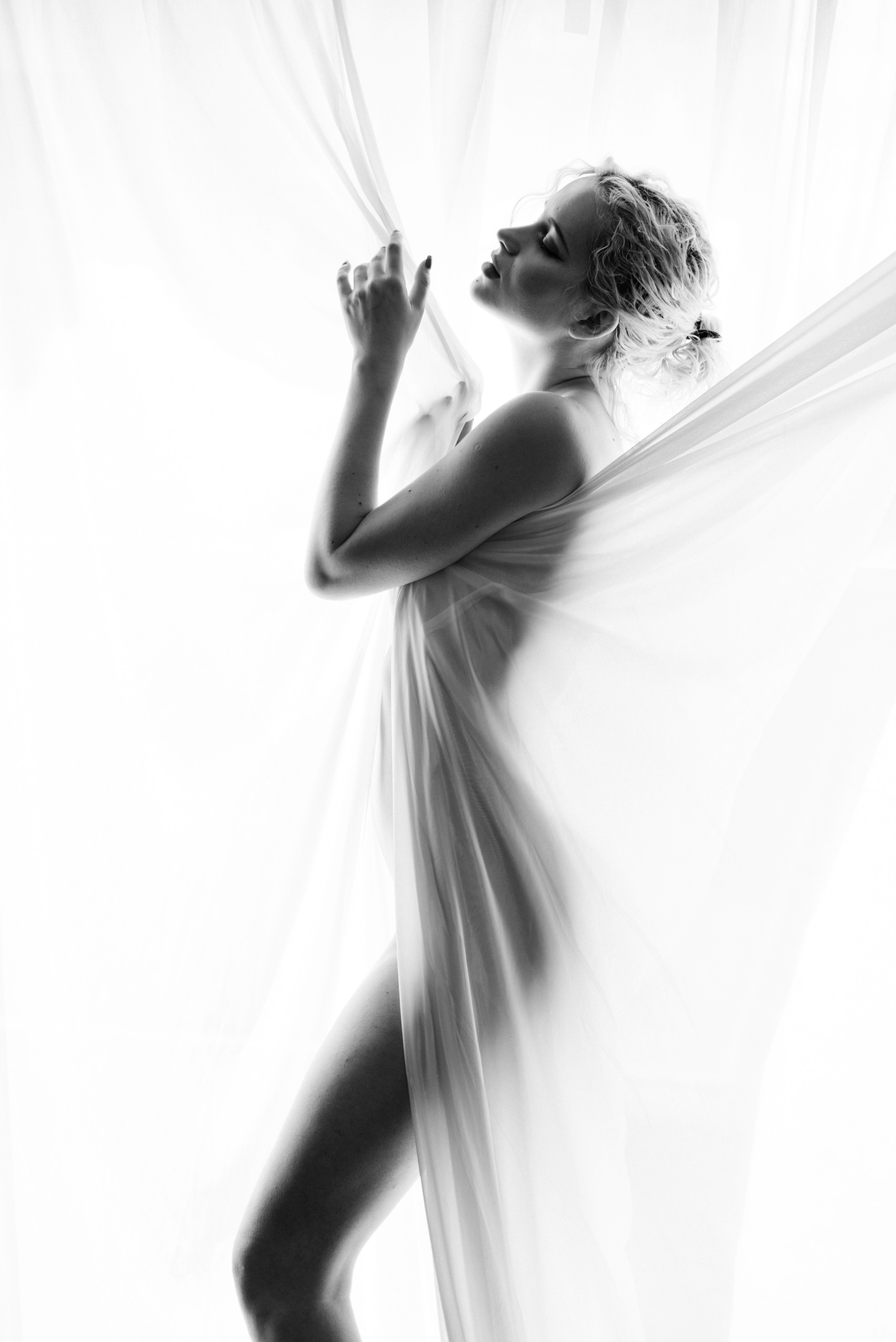 Artistic boudoir photography London — silhouette of woman behind sheer curtain, sensual movement blur