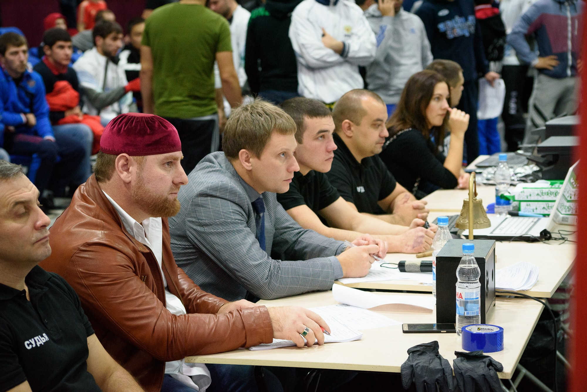 Судьи соревнования сидят за столом и следят за боем