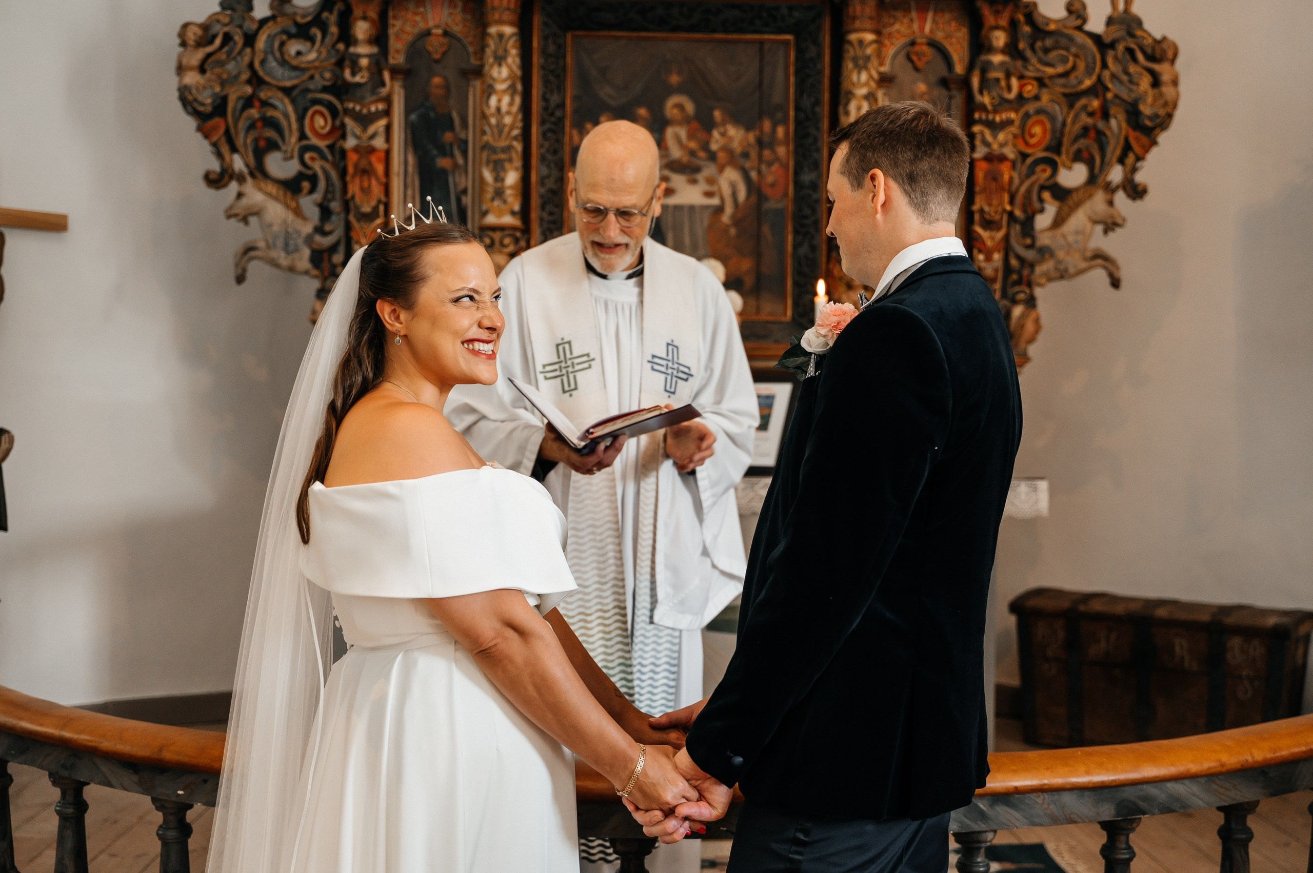 Bröllopsfotografering i kyrkan – detaljer från ceremonin med brud och brudgum i fokus. Wedding photography in church – ceremony details with bride and groom in focus.