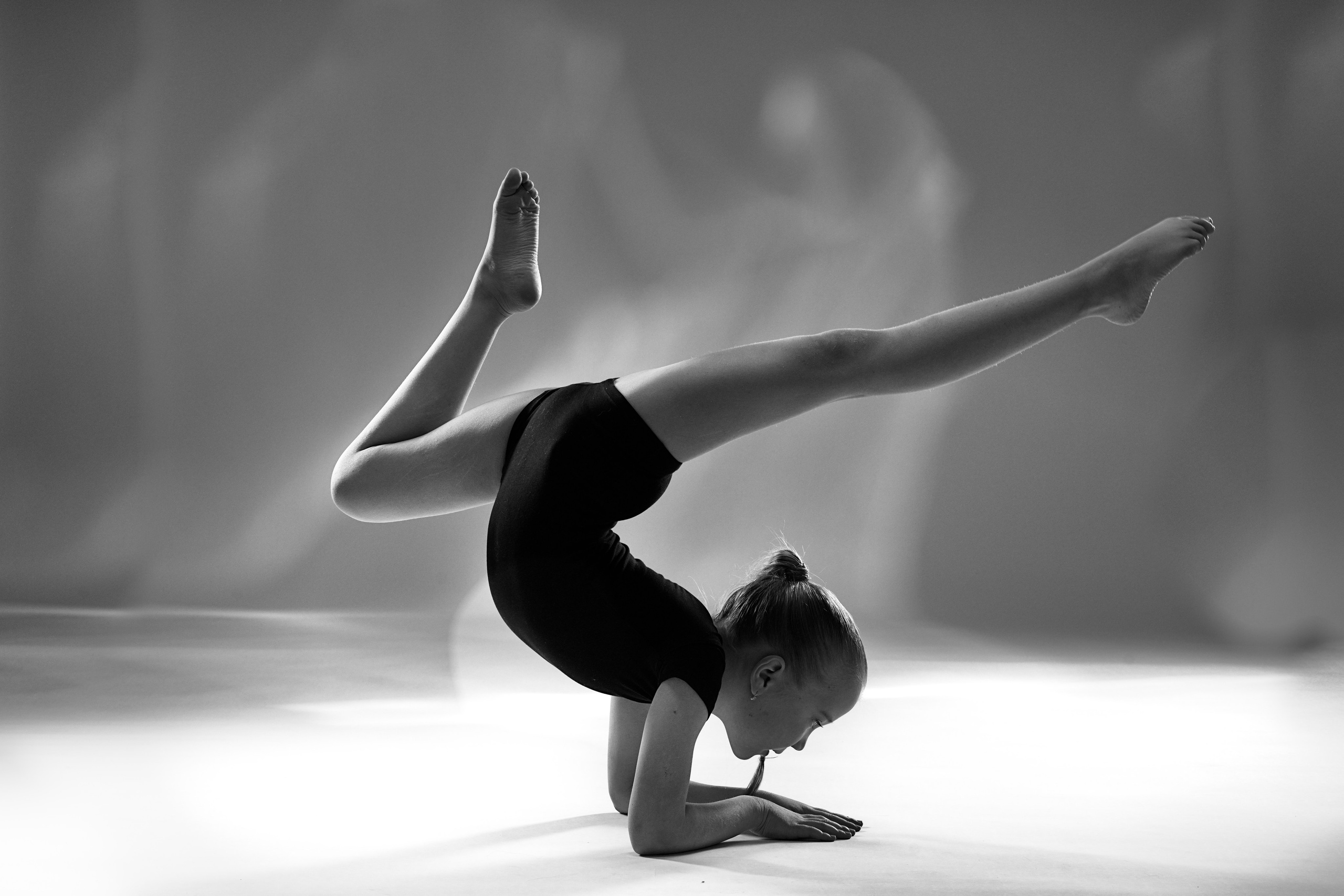 Черно-белое фото гимнастки в стойке на предплечьях, художественный прогиб и баланс, профессиональная спортивная съемка в Тюмени