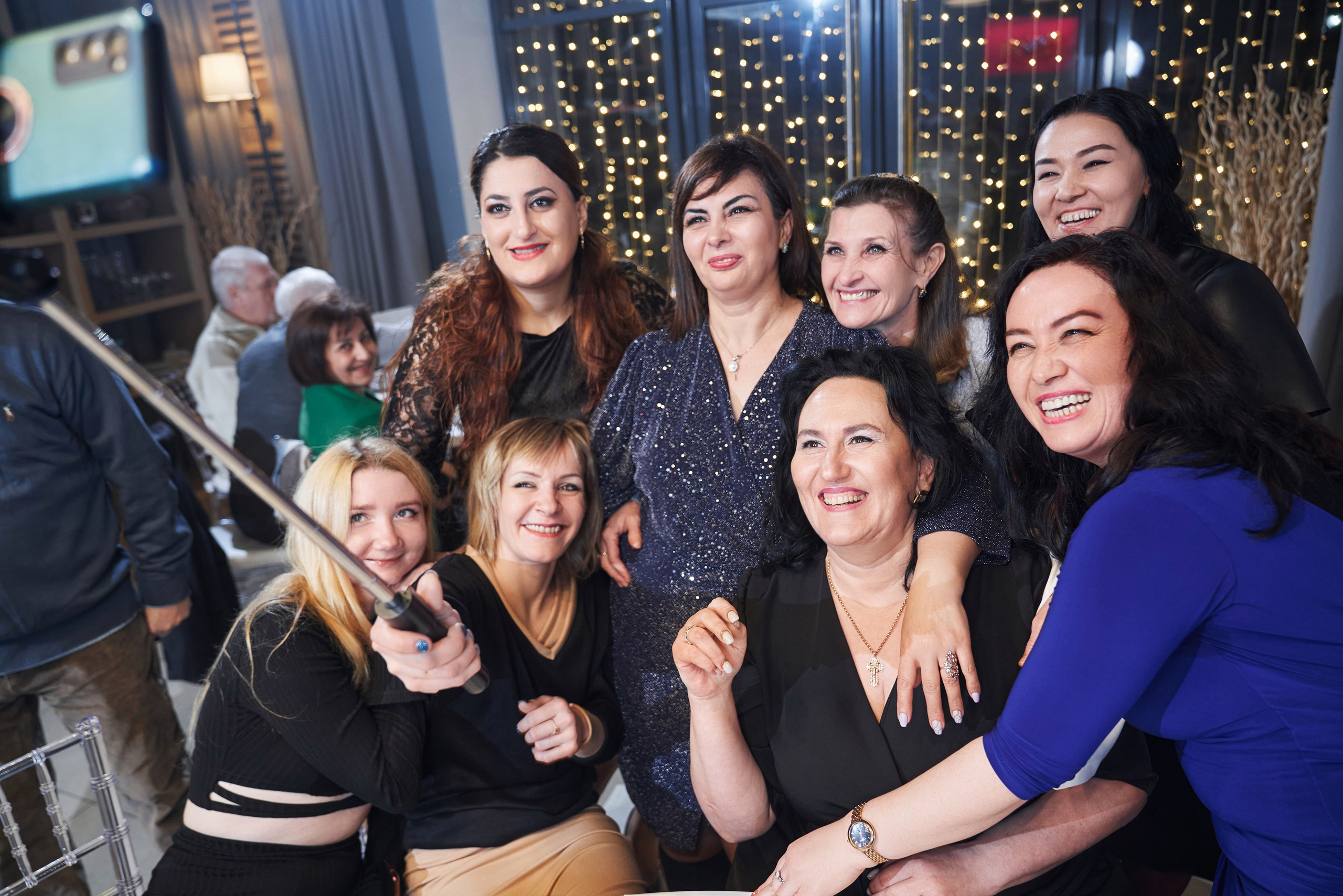 групповое селфи девушек на айфон с селфи палкой за столом