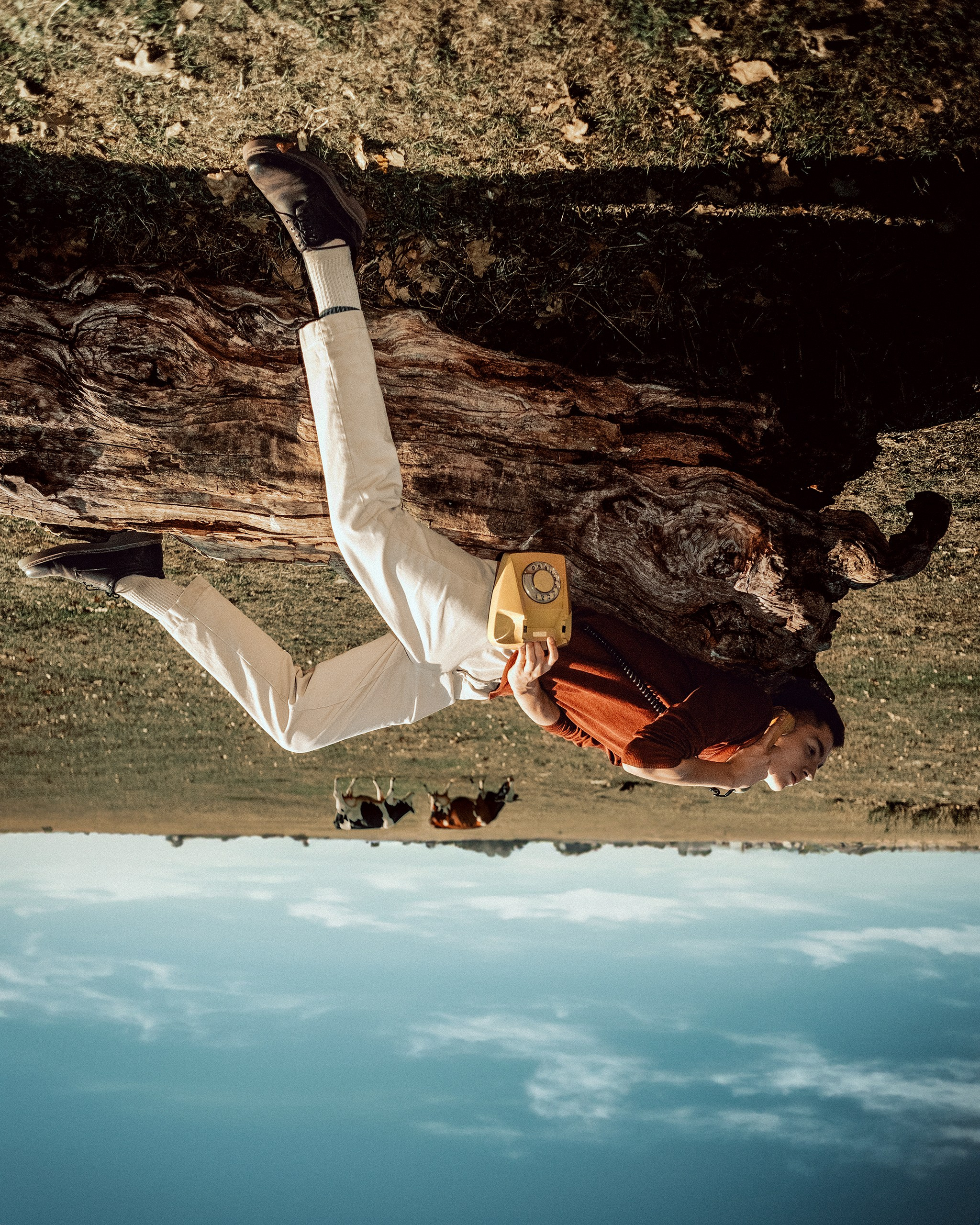 Молодой парень лежит на бревне в поле и разговаривает по телефону, дневная мужская съемка