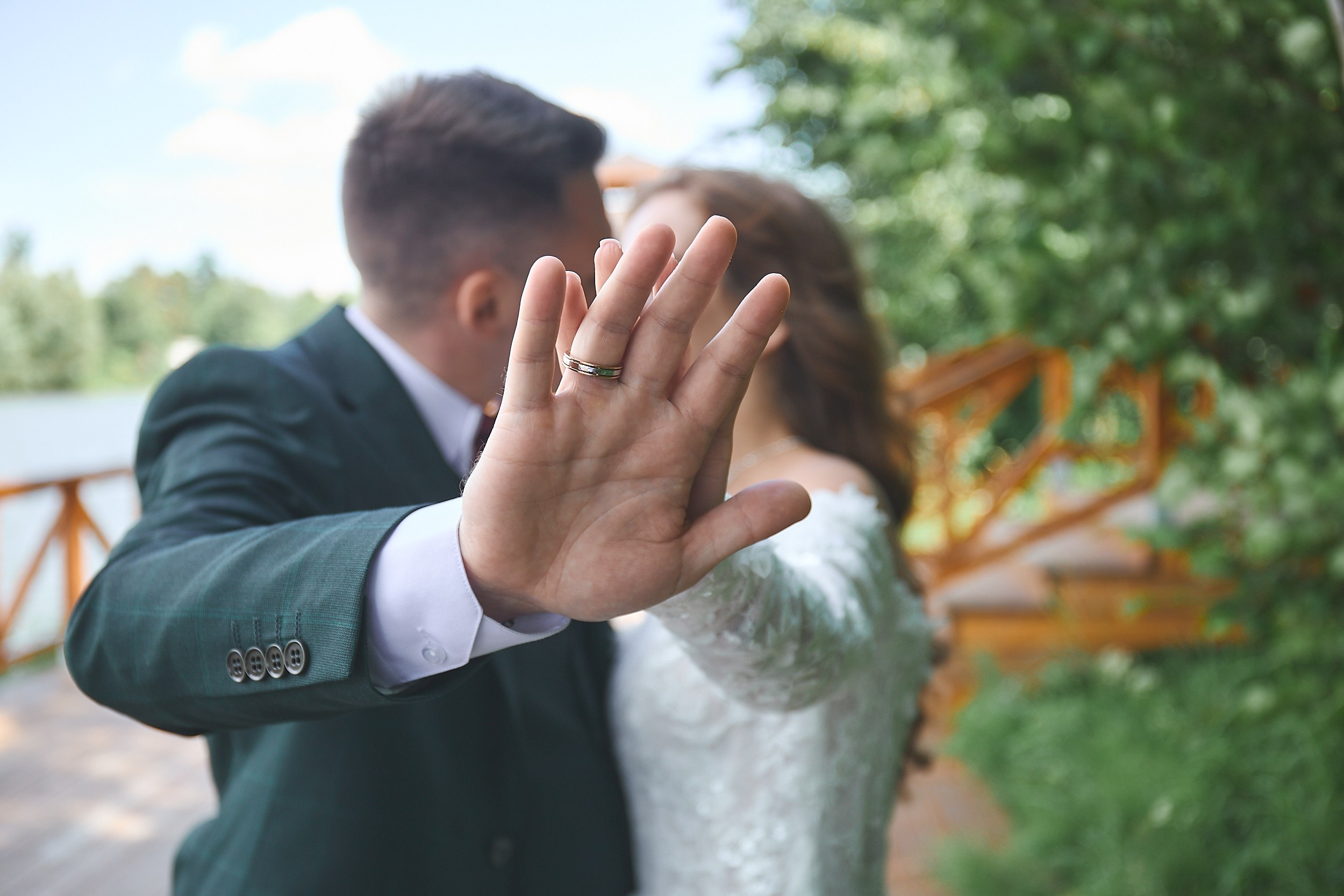 Жених закрывает рукой поцелуй с невестой