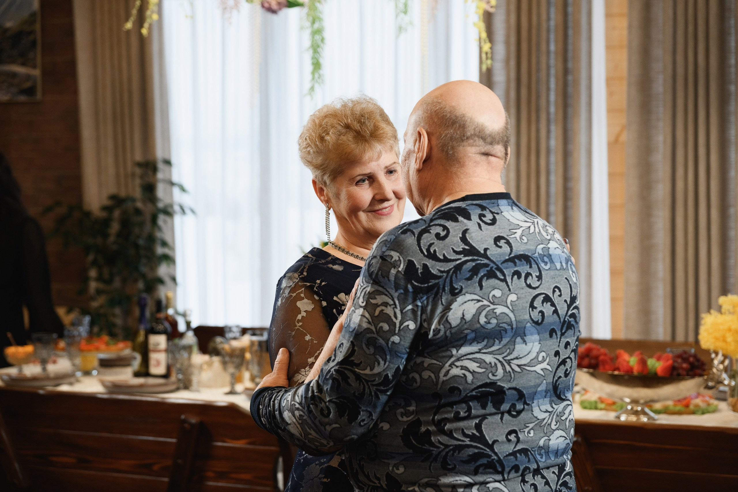 Пожилая пара танцует на семейном празднике за праздничным столом, тёплая атмосфера и живые эмоции, Петропавловск-Камчатский.