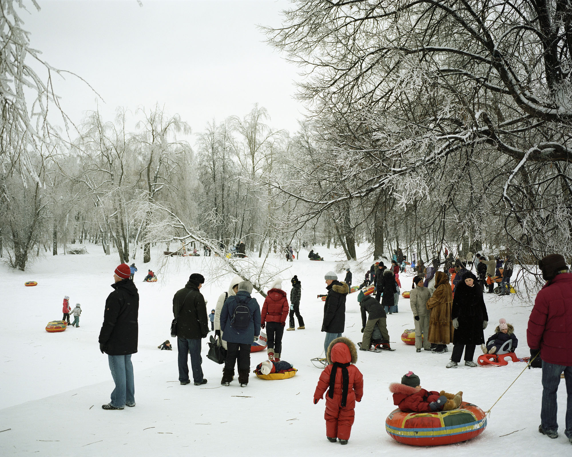 PLATE 12: Figures of people at leisure (with assorted sledges and snow tubes, baby strollers), trees, winter landscape