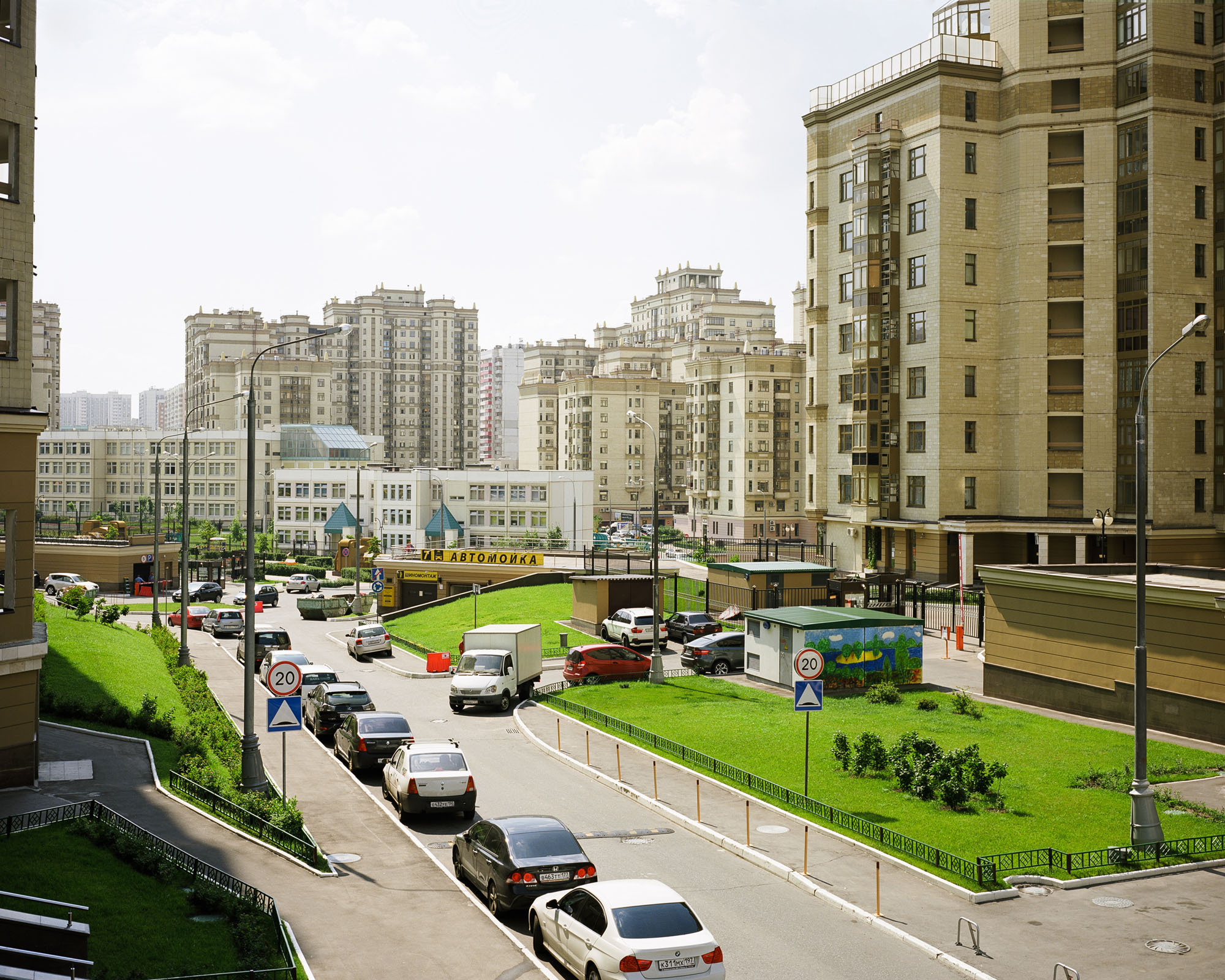 PLATE 62: Modern residential buildings, school buildings, speed bump, signage, lamp posts, lawn, bushes, assorted barriers, cars, road signs, assorted small buildings and guard houses, boom gates, waste skips