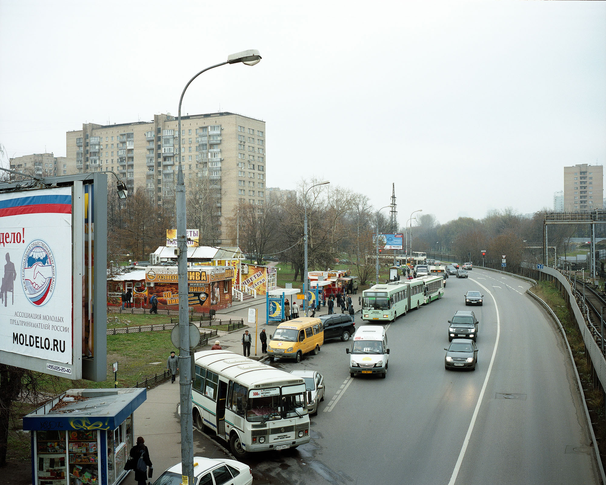 PLATE 56: Residential buildings, mini buses, buses, kiosks, bus stops, lamp posts with power lines (also includes trees, assorted barriers, billboards and signage, figures of people, cars, rail tracks, grass, road signs, A/C units, 	traffic lights, high voltage tower)