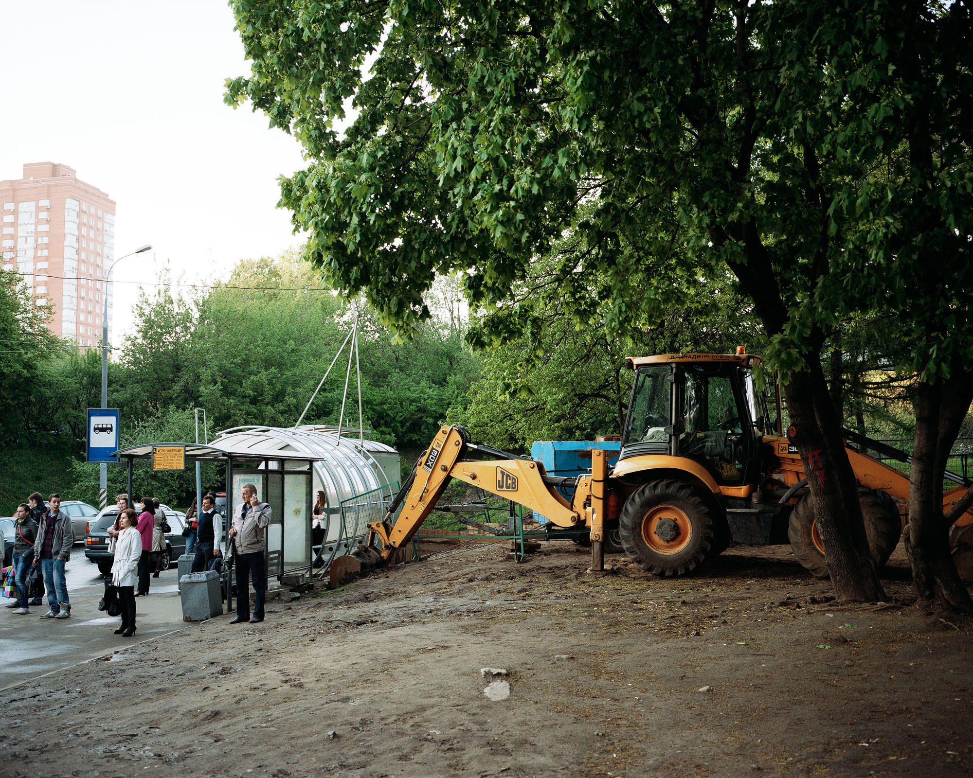 PLATE 23: Bus stop with assorted shelters, waste bins, figures of people, trees, sand, JCB digger, portable construction barriers, lamp posts, residential buildings, cars