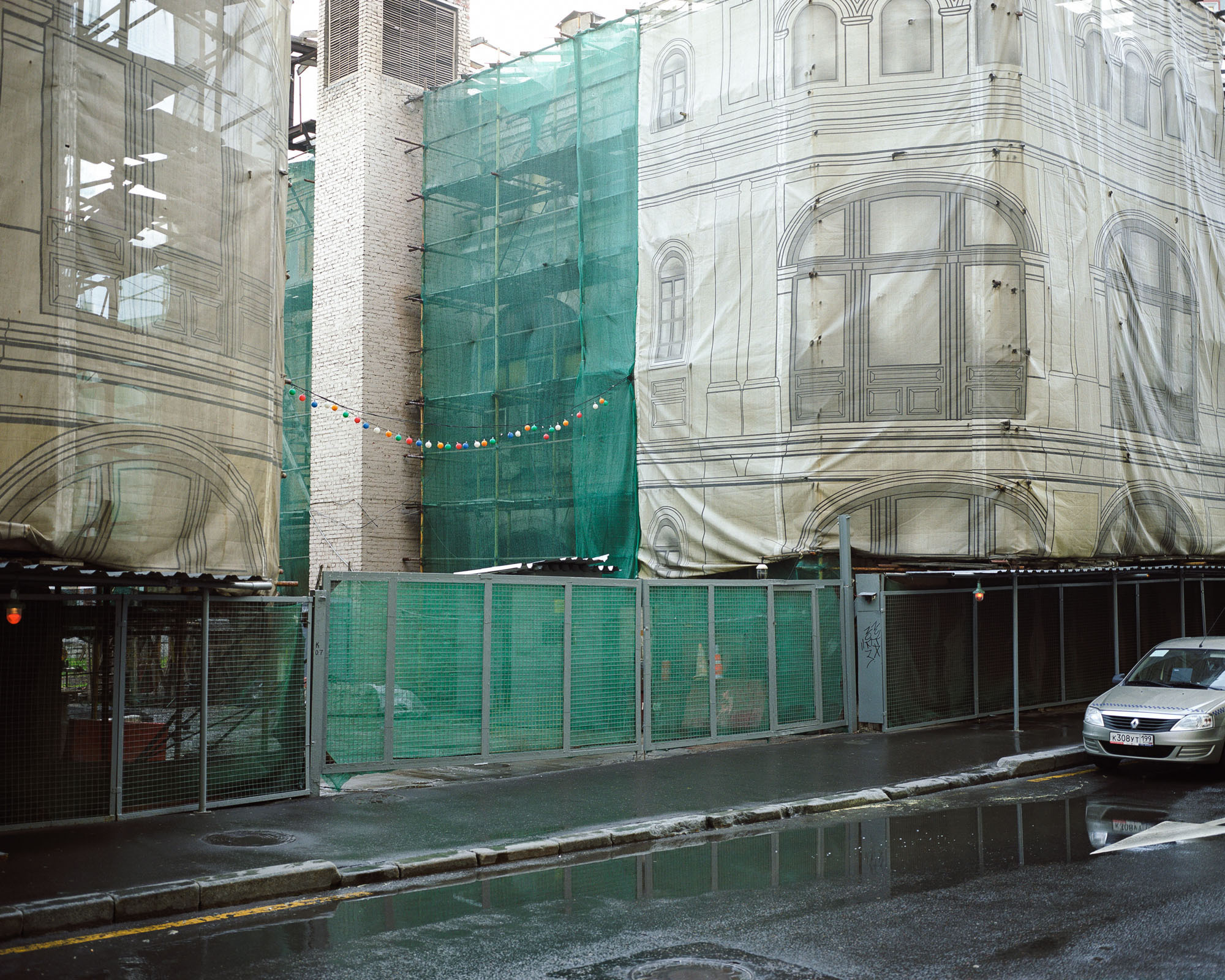 PLATE 37: Buildings under construction c/w printed canvas façade covers and net, assorted barriers, scaffolding, warning lights, gates, sheltered walkway, car, multi-colored bulb decoration