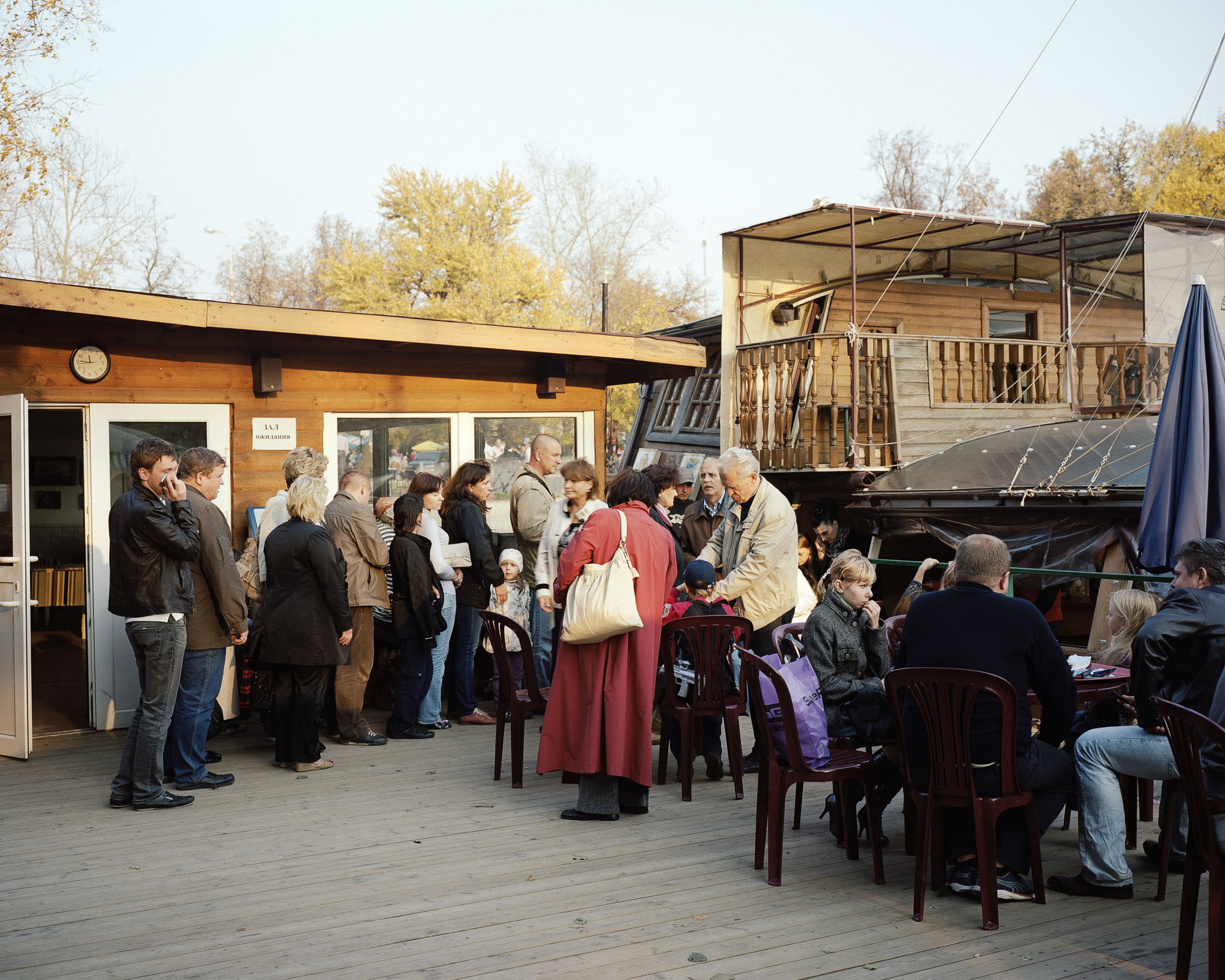 PLATE 46: Figures of people at leisure, outdoor furniture, parasol, wooden pavilion (c/w clock, loudspeakers, poster), pleasure barge, trees