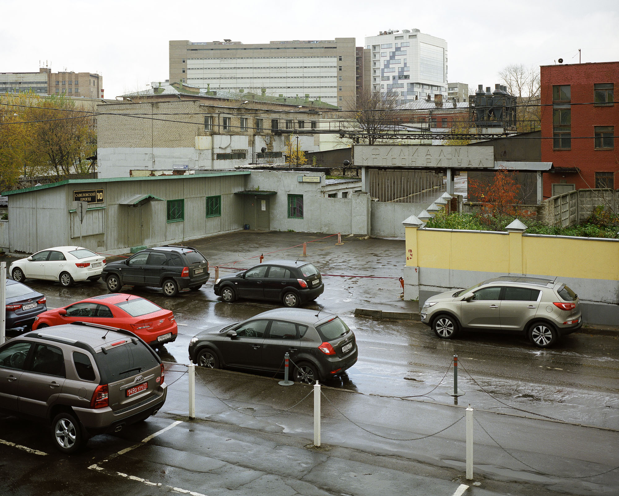 PLATE 29: Non-residential buildings (concrete, brick, wood), painted wall, concrete modular wall, sliding gate, signs, trees, assorted barriers, chimneys (also includes trees, cars, parking space)