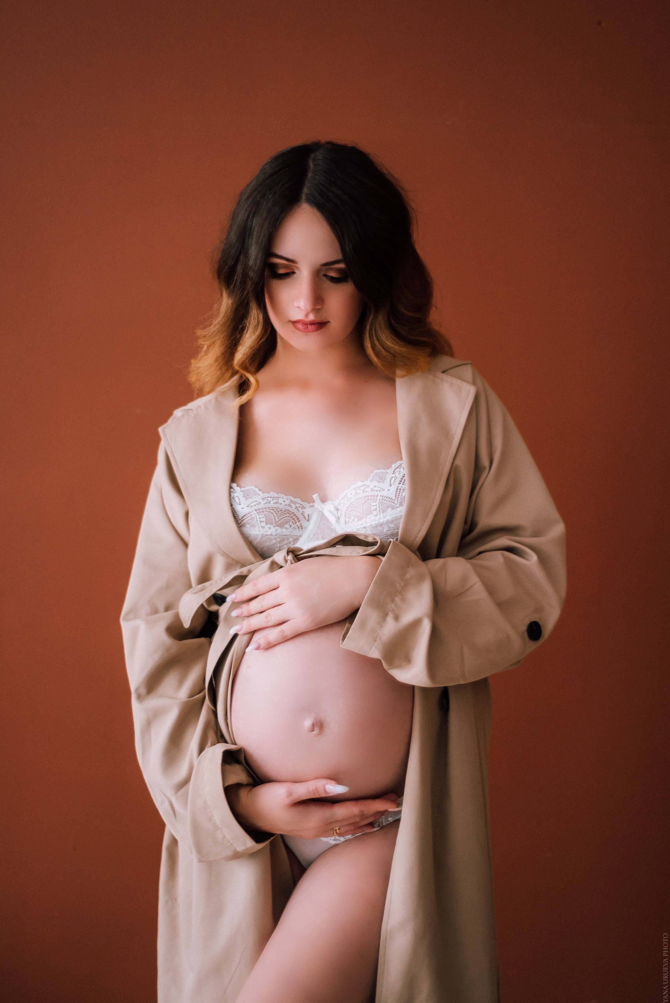 Беременная девушка в белом белье и бежевом тренче