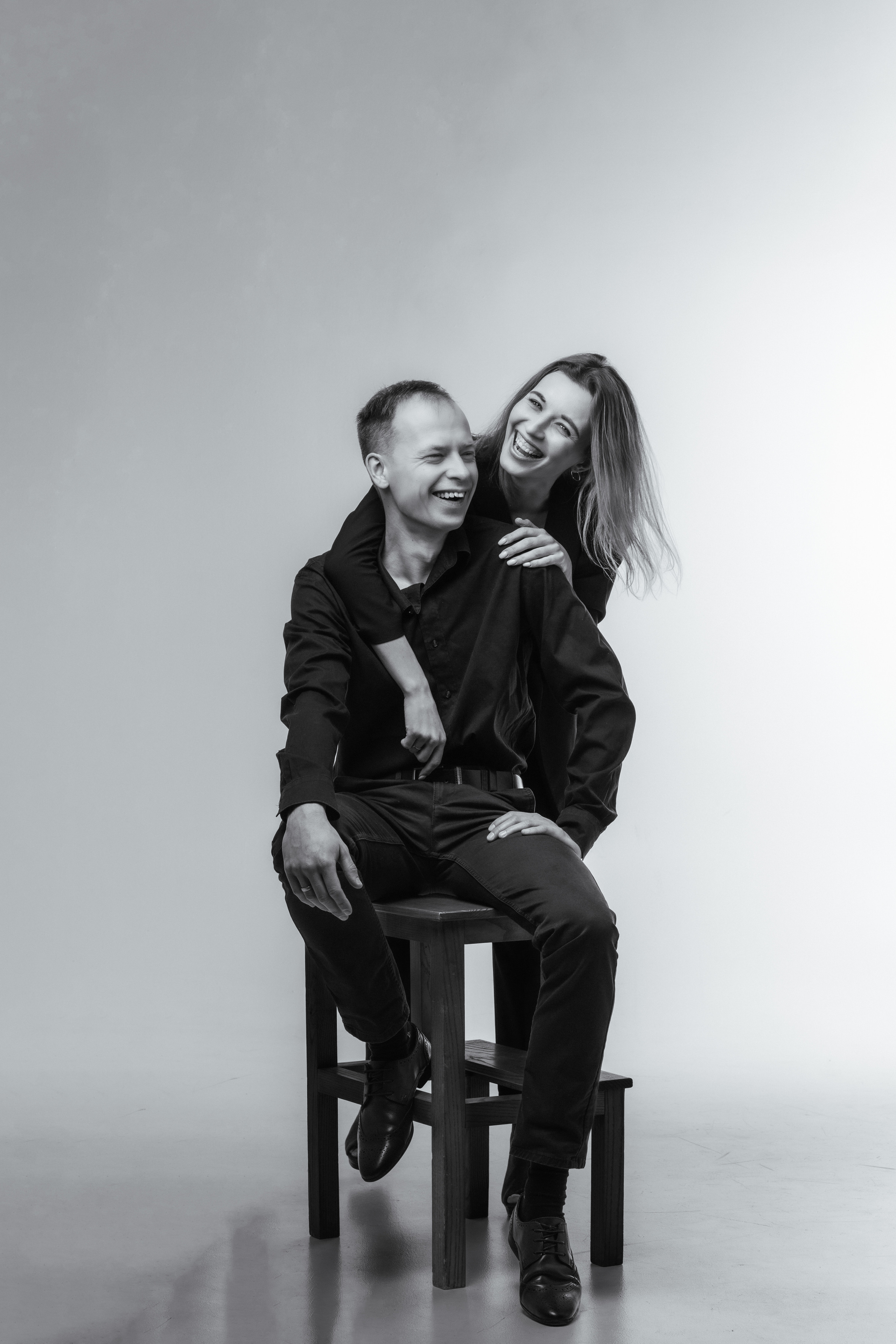 Съёмка lovestory девушка в пиджаке обнимает мужчину сидящего на стуле