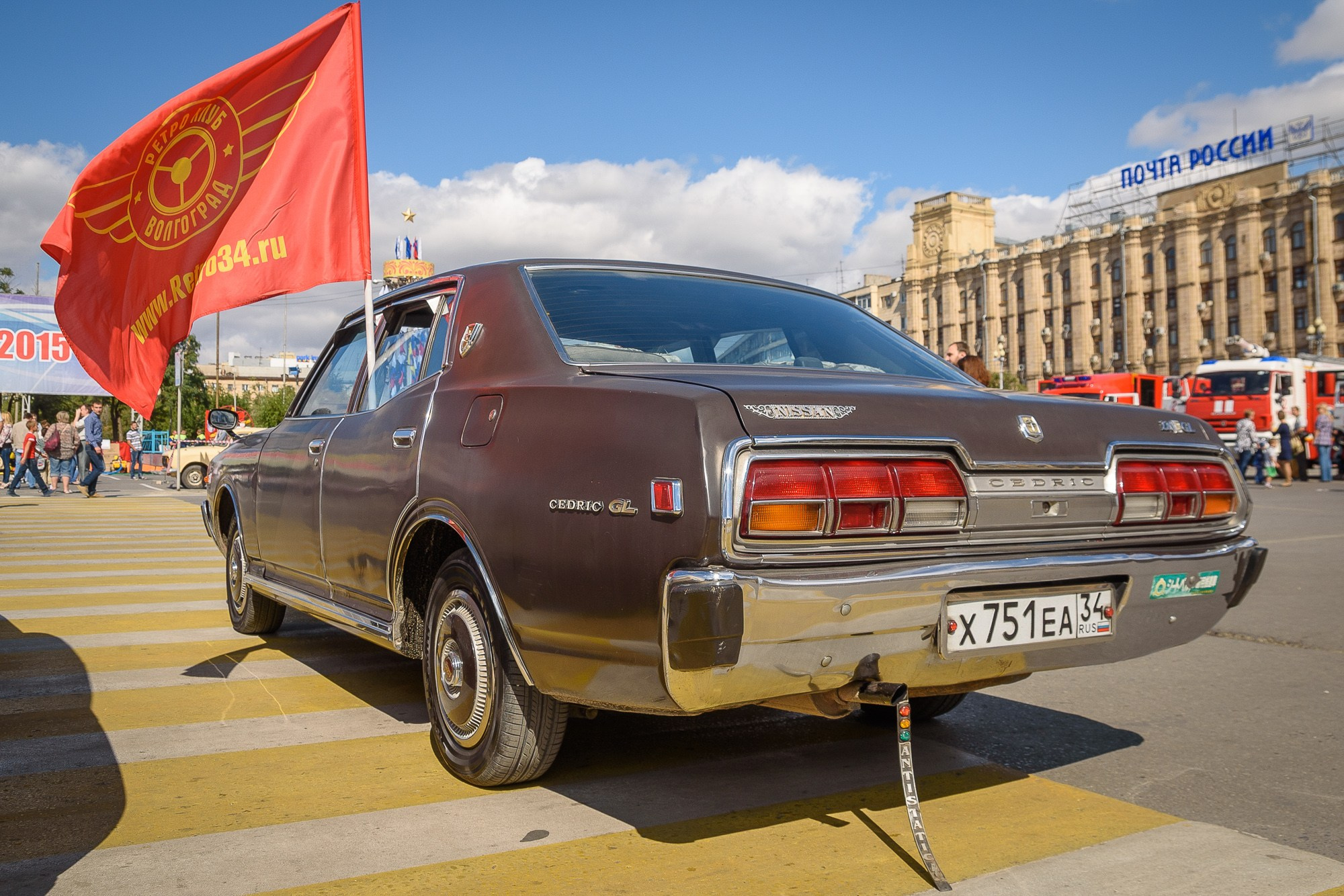 Nissan Cedric с флагом ретро-клуба на площади, вид сзади