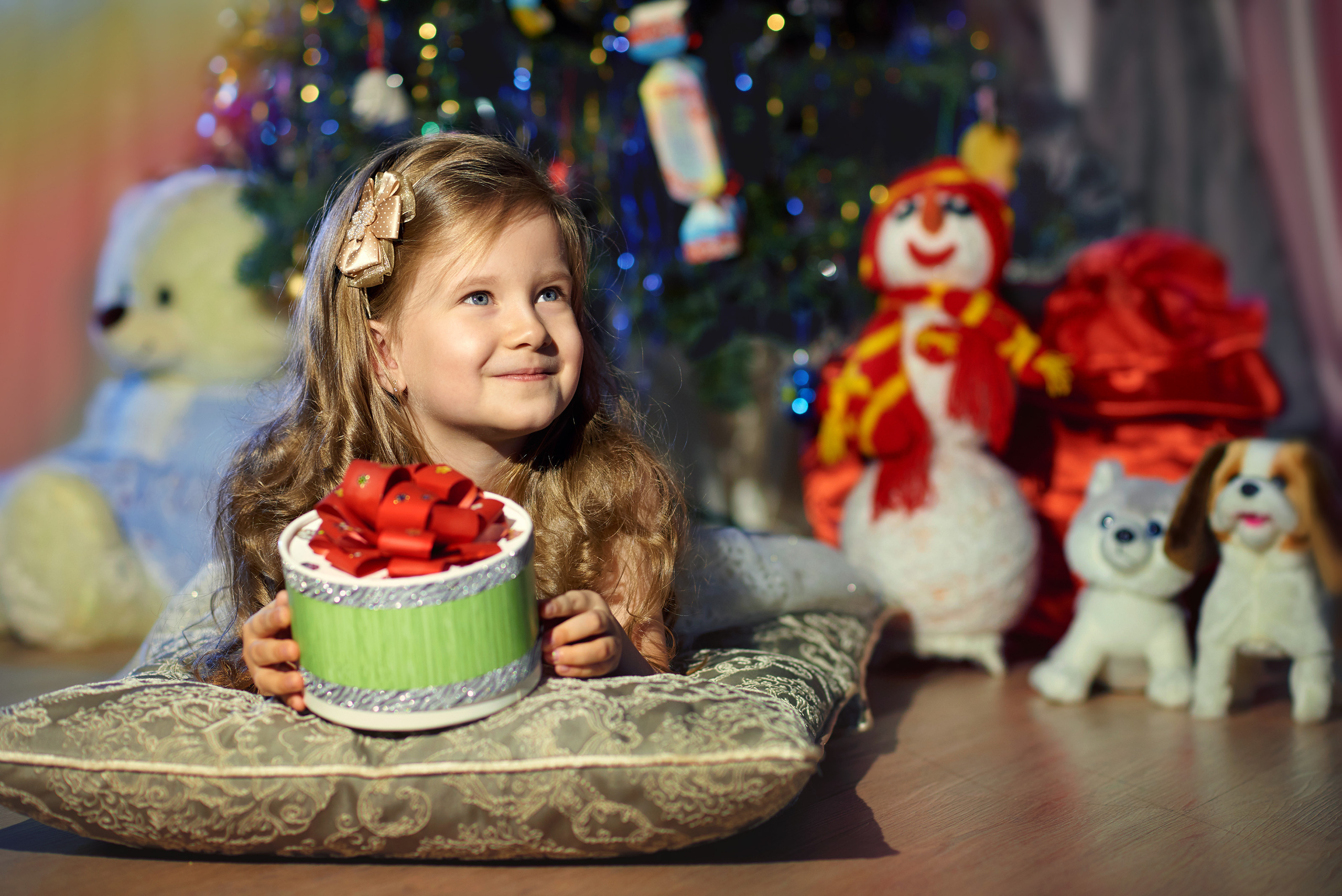 новогодняя фотосессия с ребенком - портрет девочки с подарком и игрушками на фоне ёлки