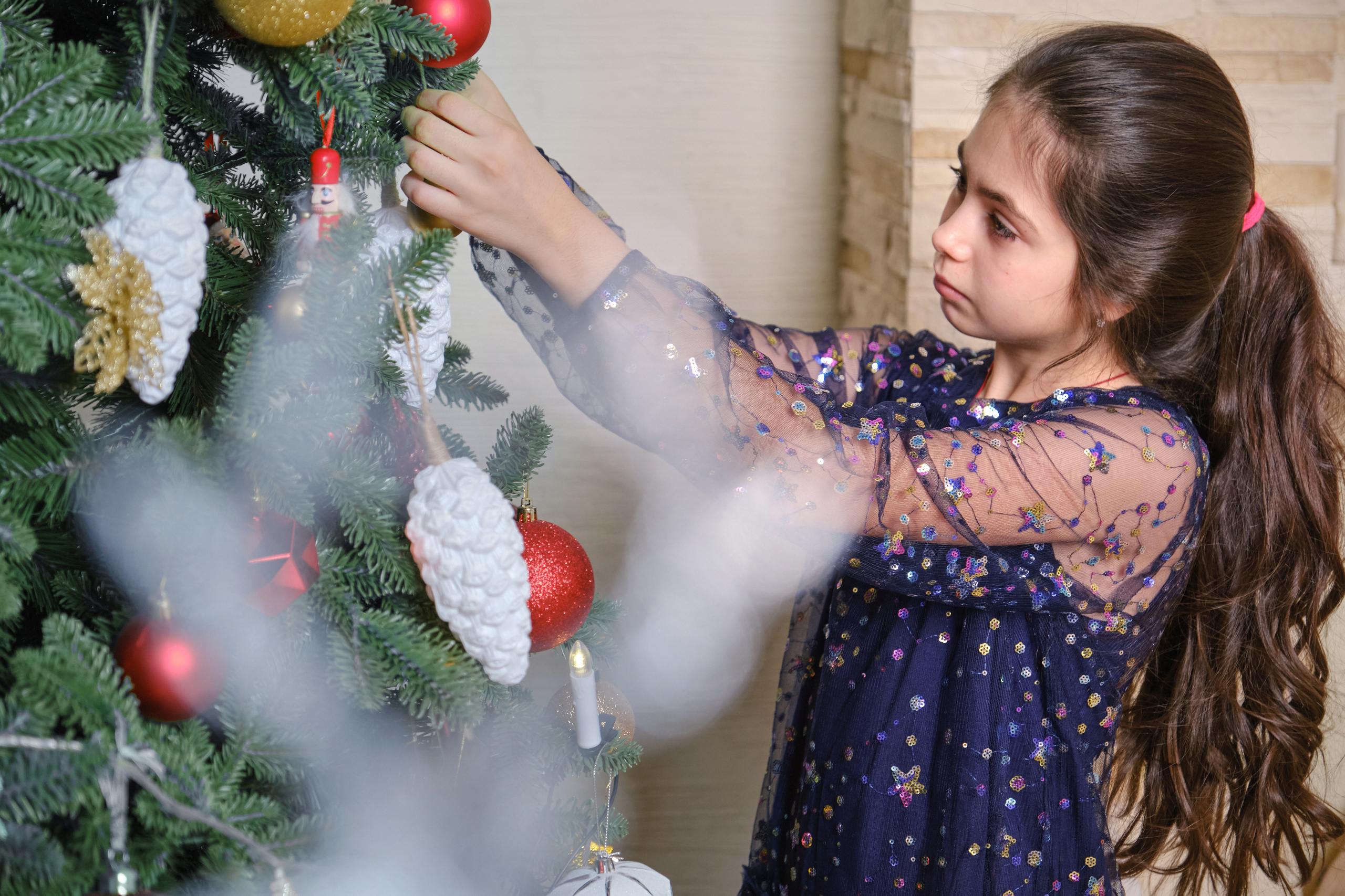 новогодняя фотосессия с детьми в студии - девочка наряжает ёлку