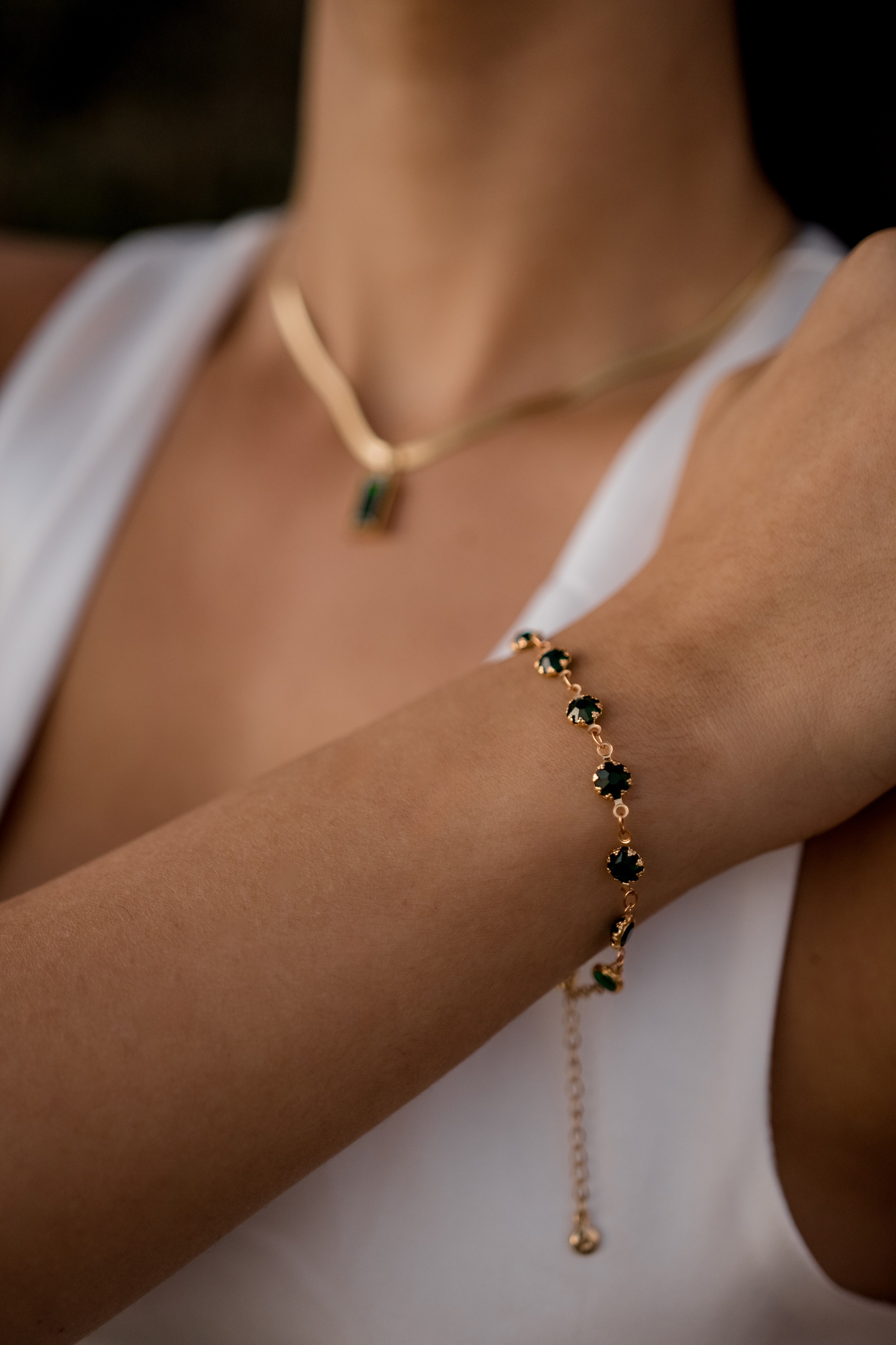 Close-up of a model’s hand wearing a delicate gold bracelet, blending beach-inspired fashion and elegance.