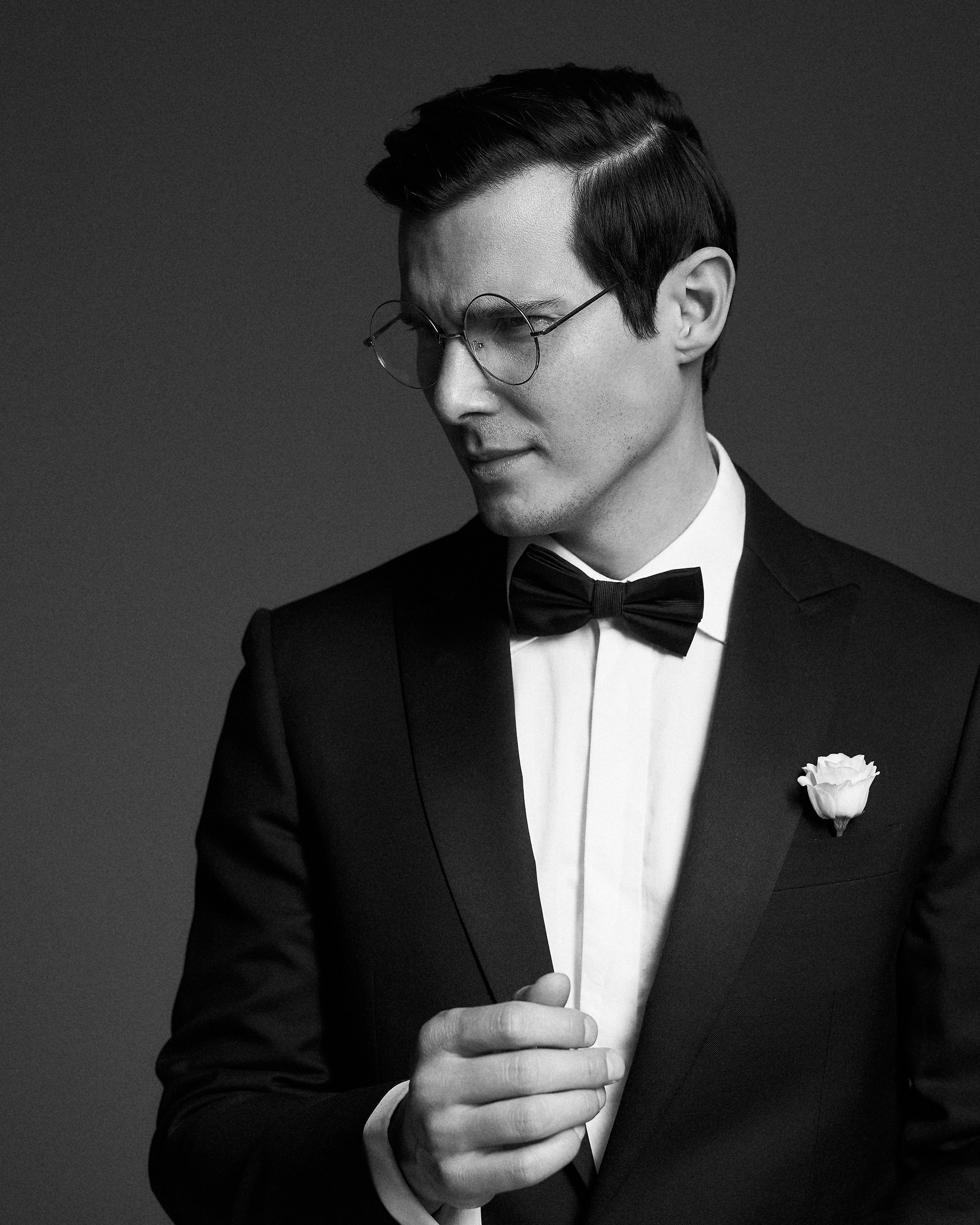 Жених в смокинге на тёмном фоне студии, живой взгляд в сторону. Никакой наигранности, только лёгкость и уверенность. Свадебная съемка в минималистичном стиле, фотограф Дмитрий Цветков, Санкт-Петербург