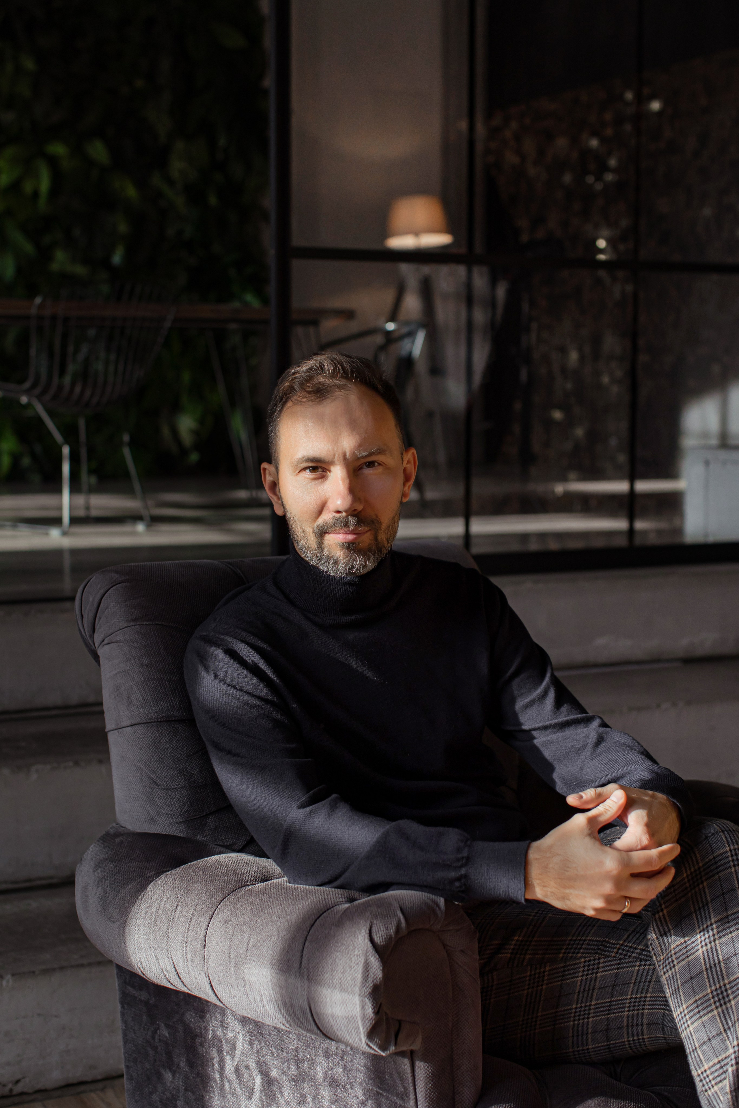 Бизнес-портрет мужчины в водолазке и брюках в интерьере