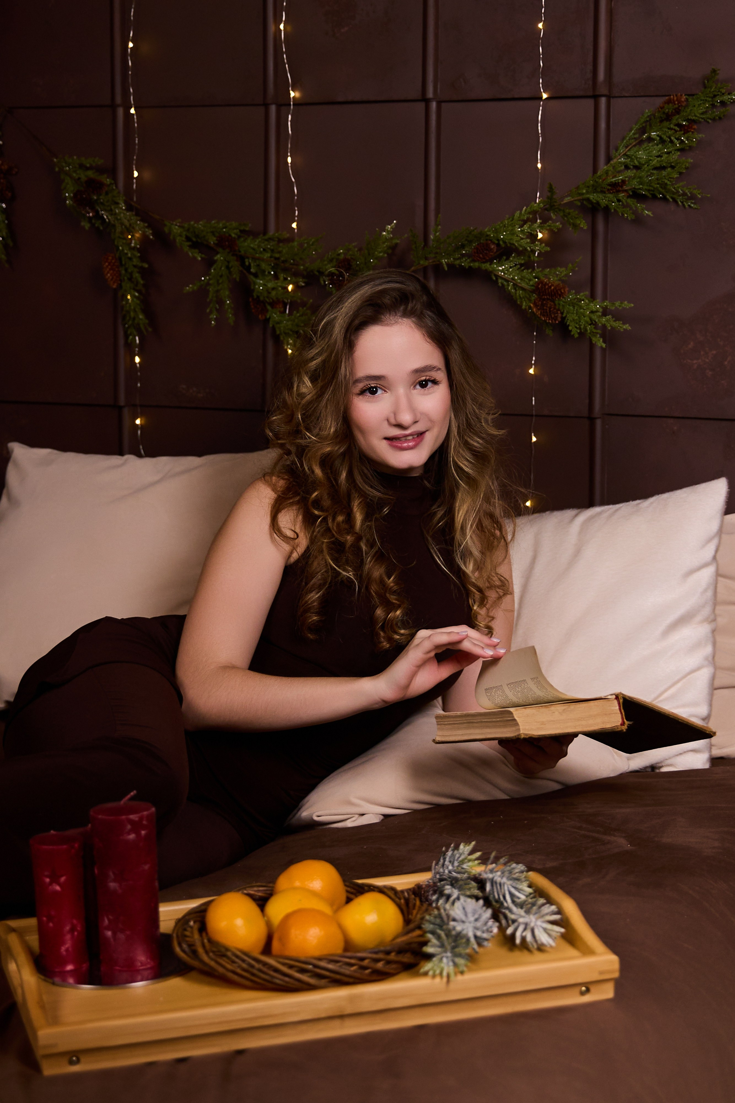фотосессия в новогодней студии девушка на кровати с книгой и мандаринами