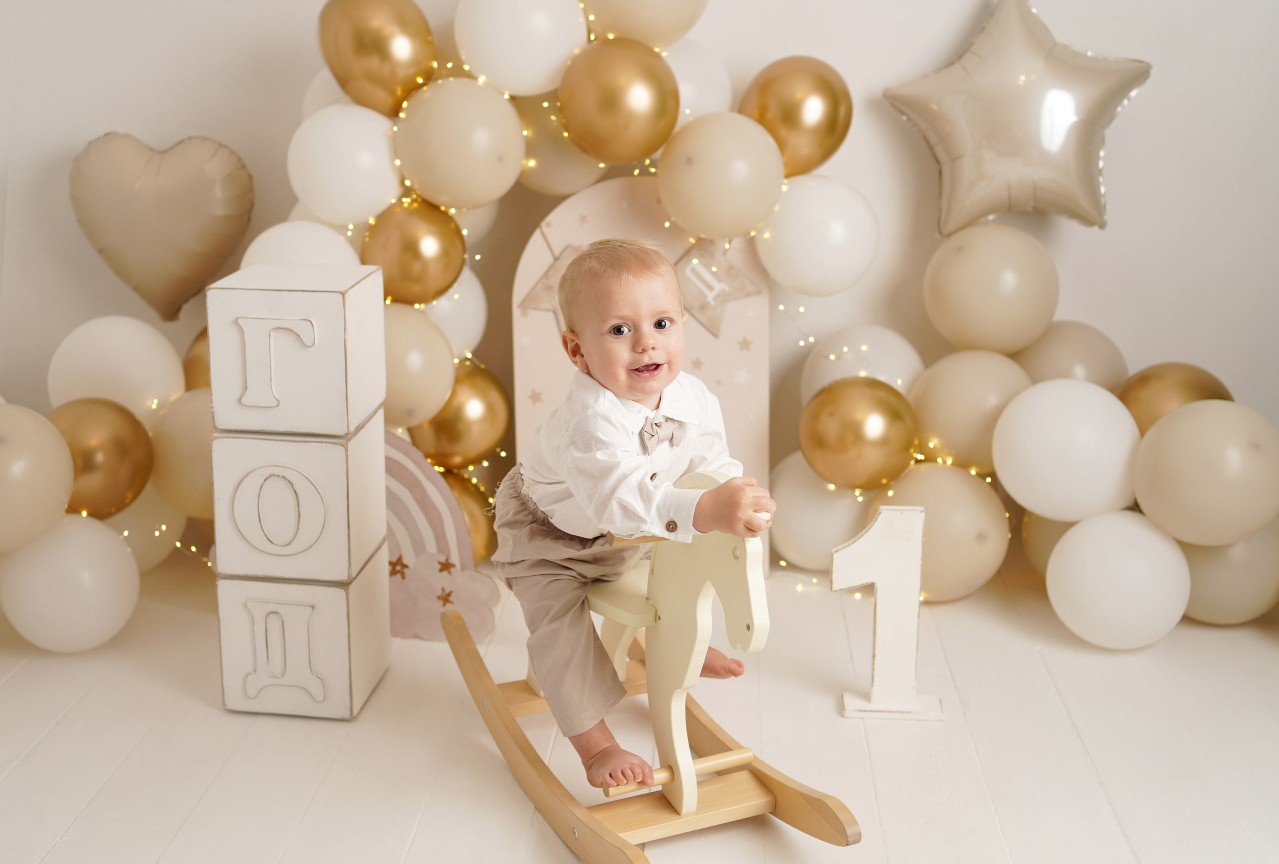 На фото малыш скачет на игрушечной лошадке, рядом кубики Год.