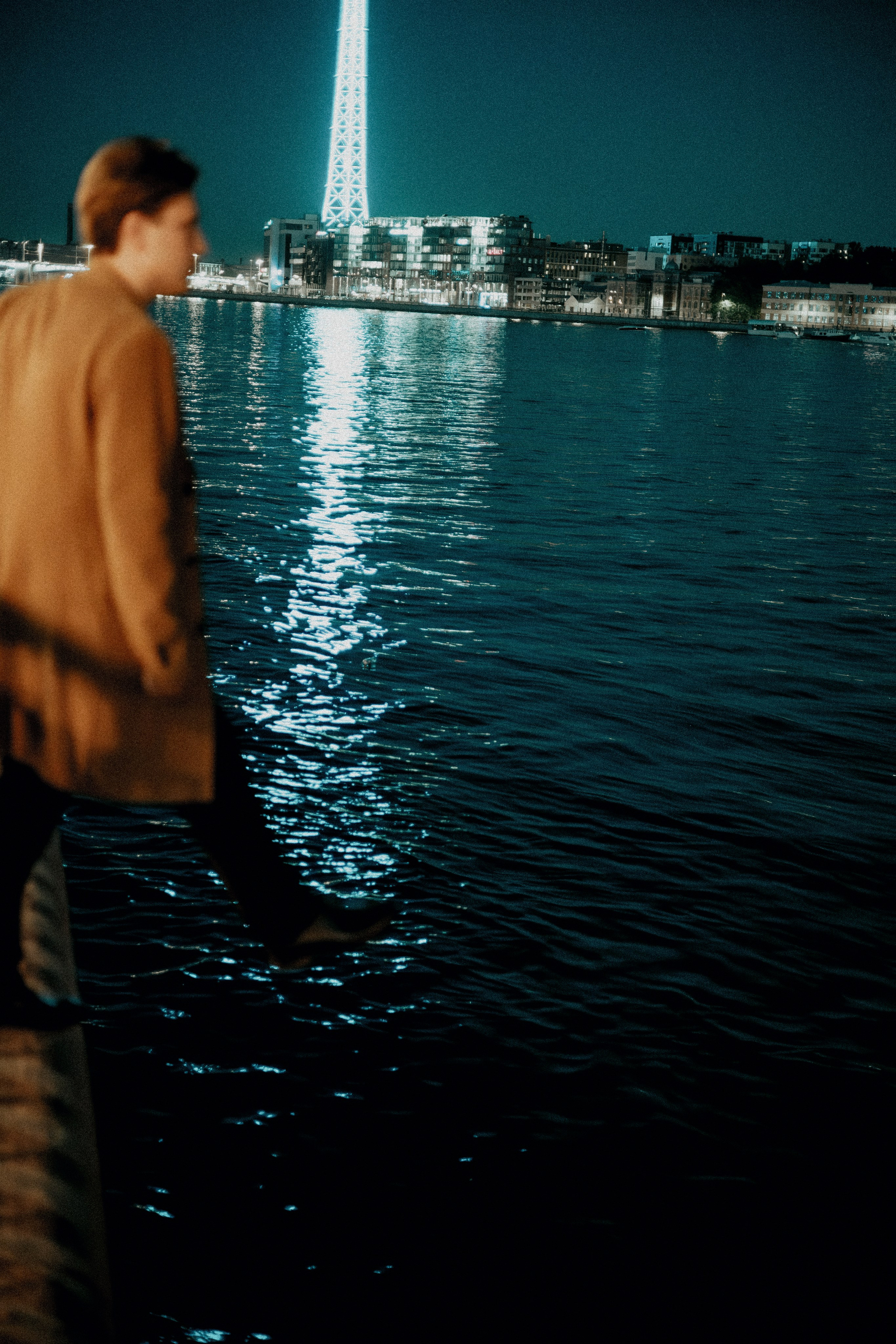 Молодой человек в пальто хочет шагнуть в воду в Питере.