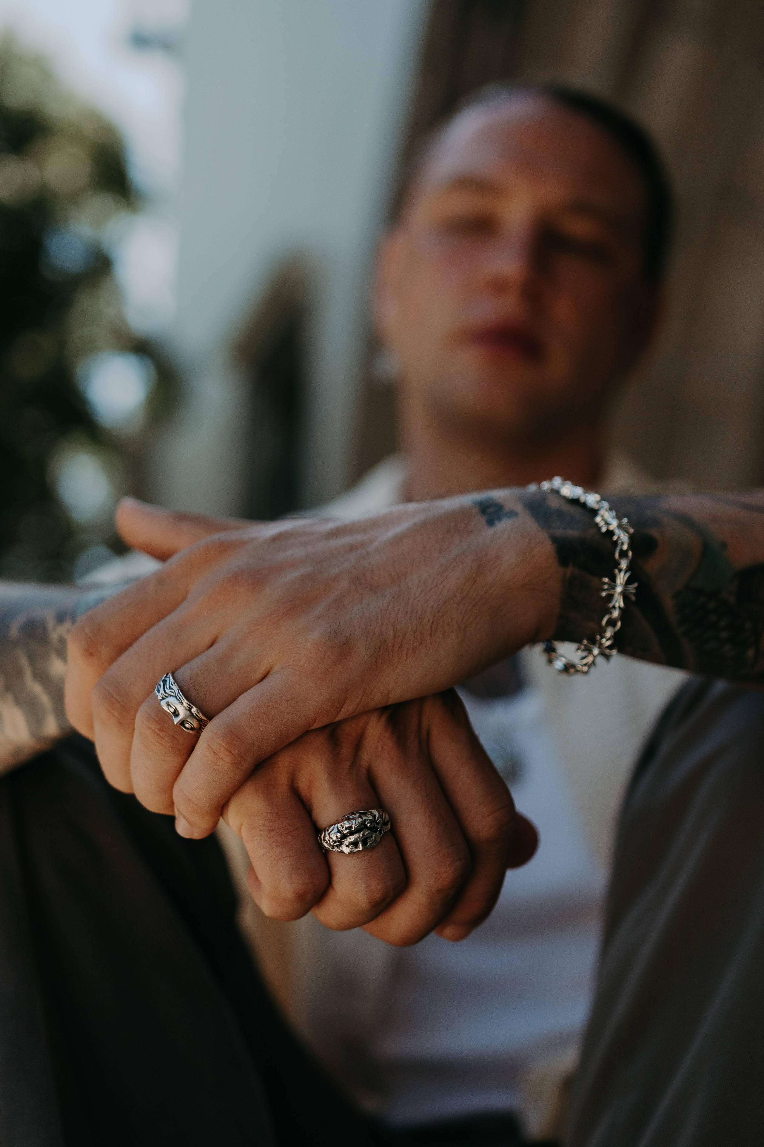 Close-up of a tattooed hand wearing a silver bracelet and ring, showcasing bold and modern jewelry design.