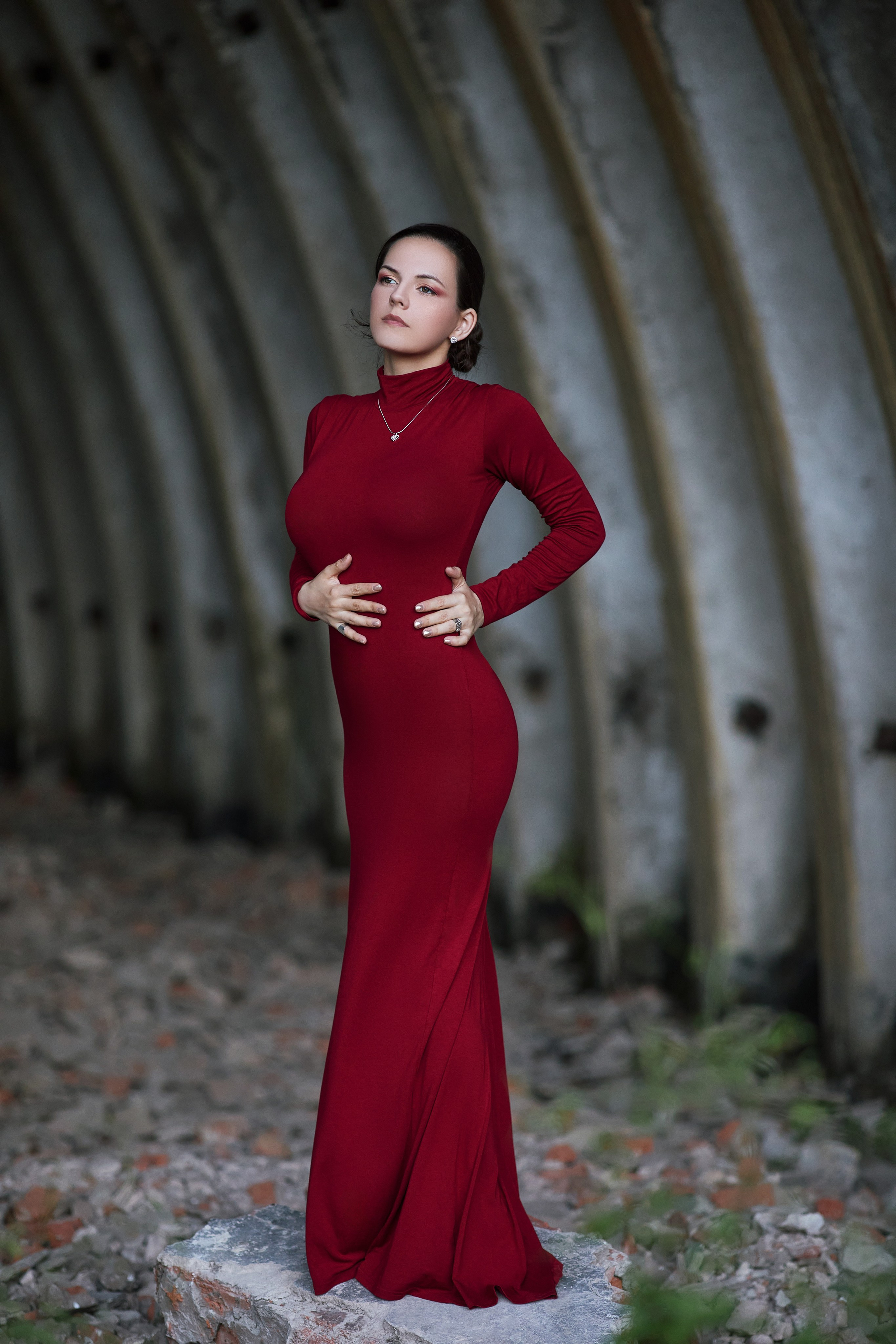 Женщина в красном платье позирует на фоне ангара