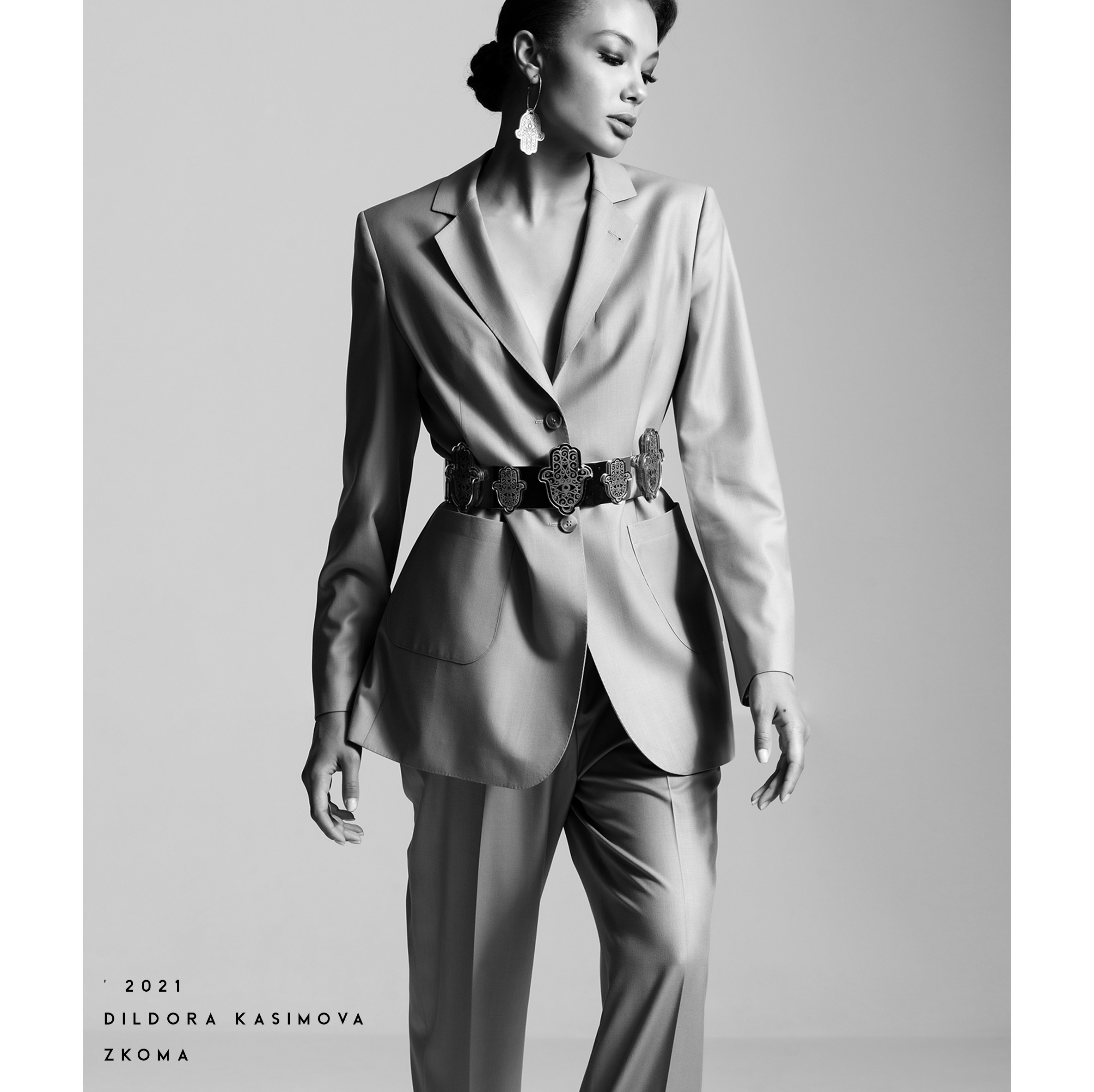 Чёрно-белая fashion-фотография светлого костюма с орнаментальным поясом и серьгами дизайнерской коллекции
