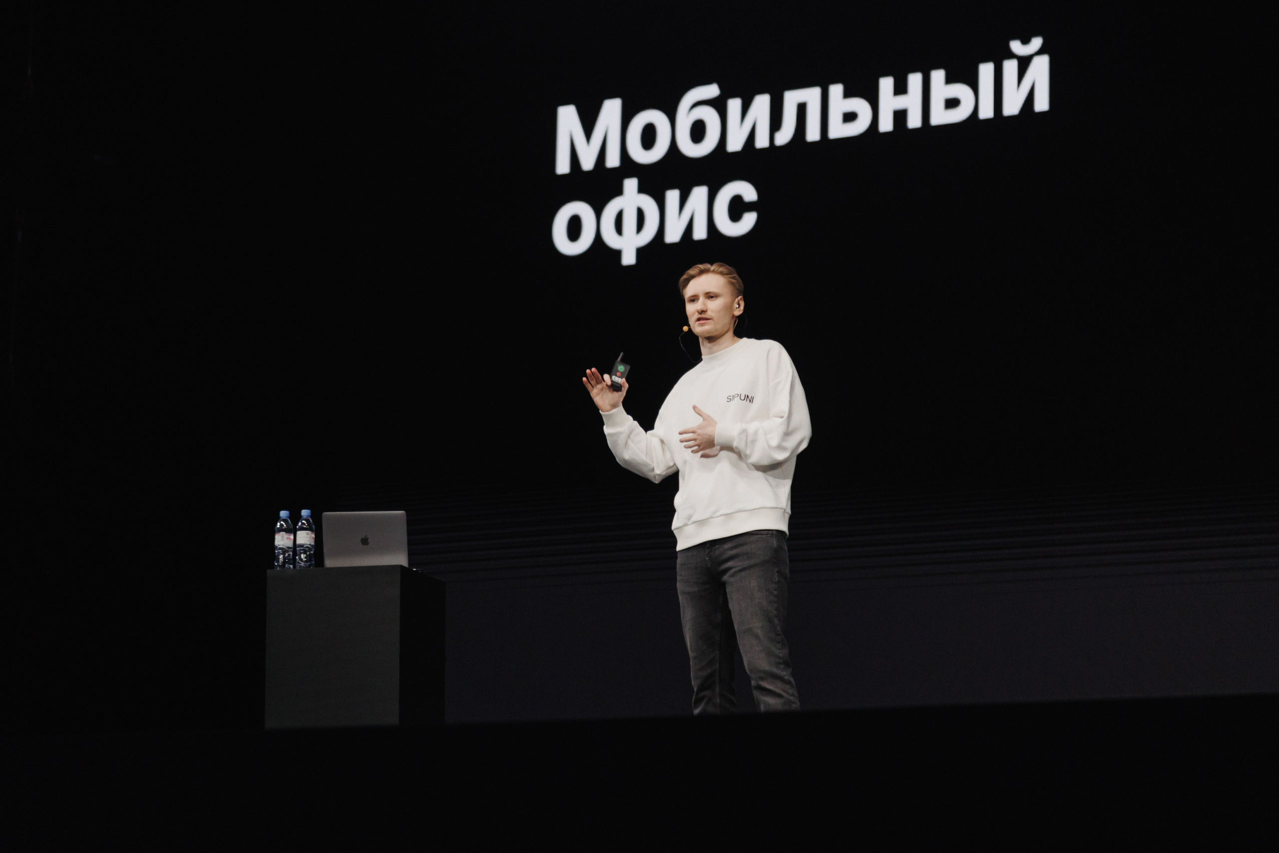 Динамичный кадр: спикер жестикулирует во время яркого выступления на сцене.