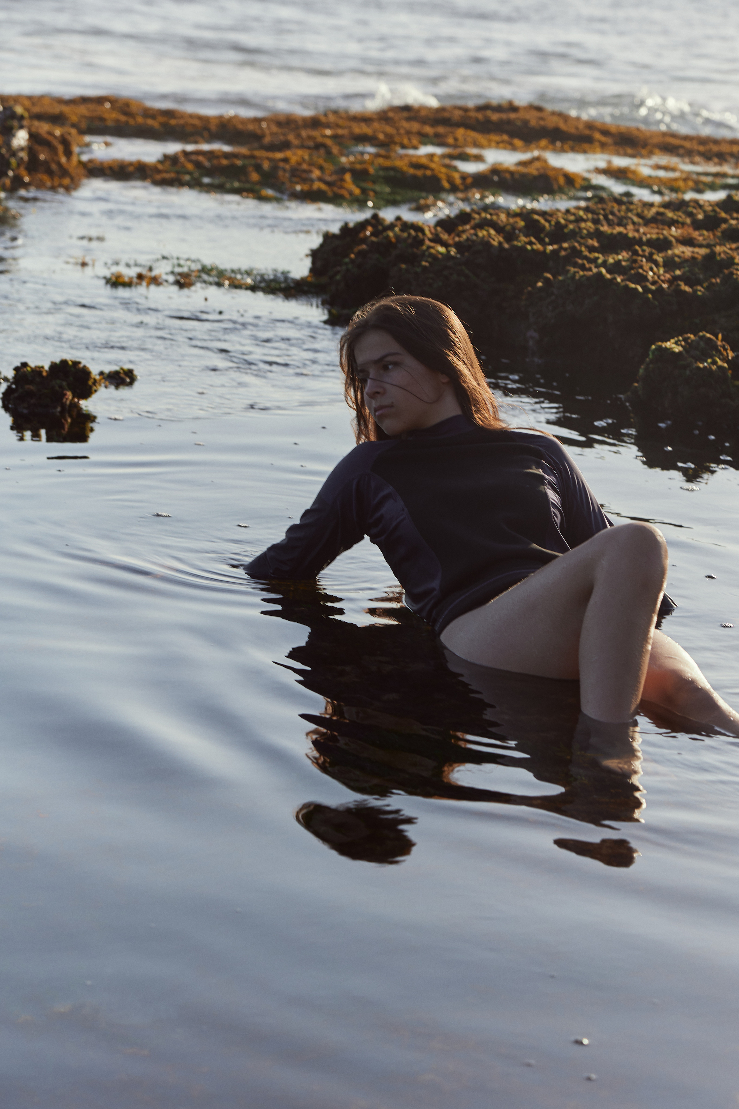 The young model lies in the water.  Sea coast background.