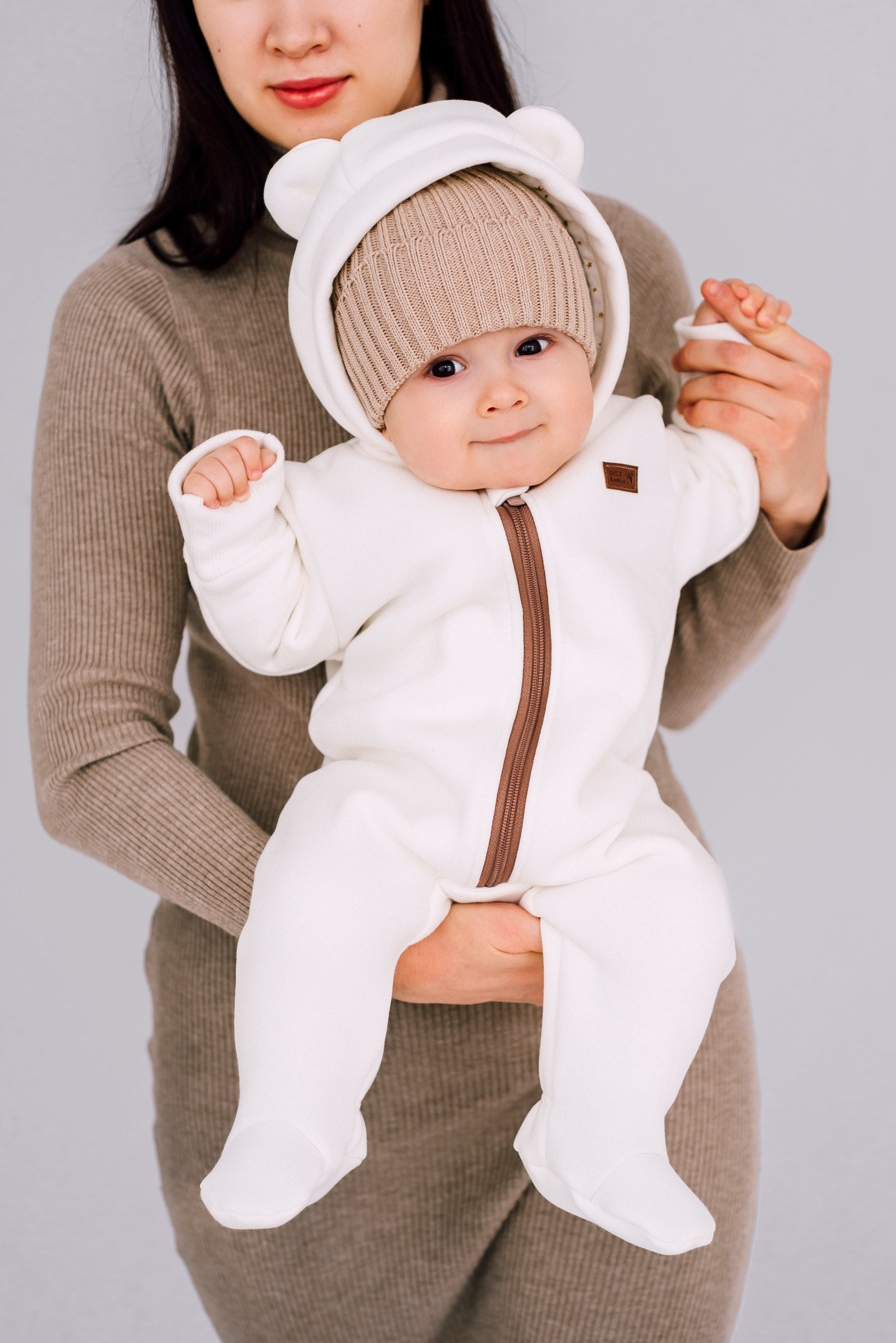 Малыш в белом комбинезоне в форме мишки