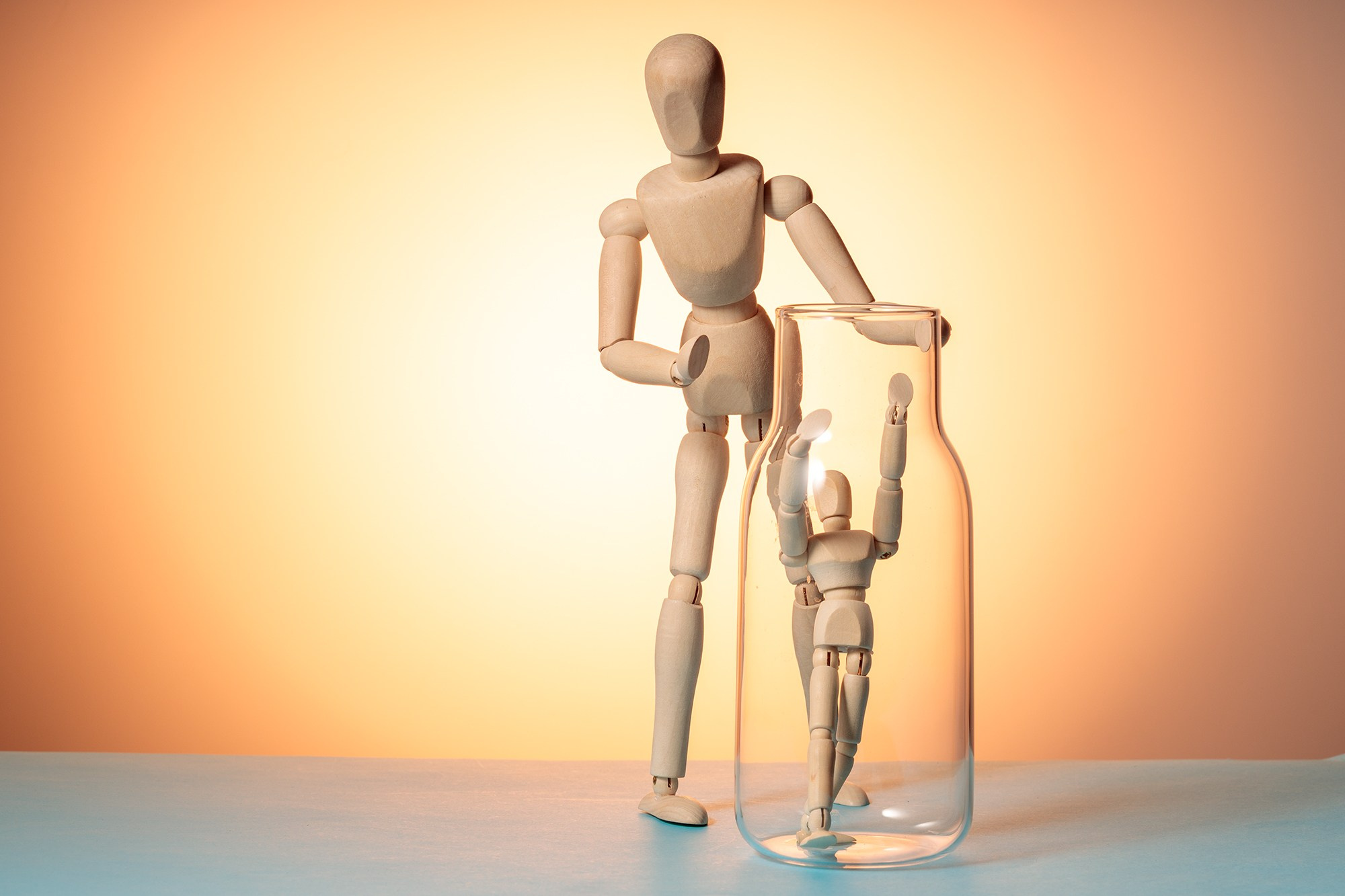 Деревянный манекен смотрит на другого манекена в стеклянной банке