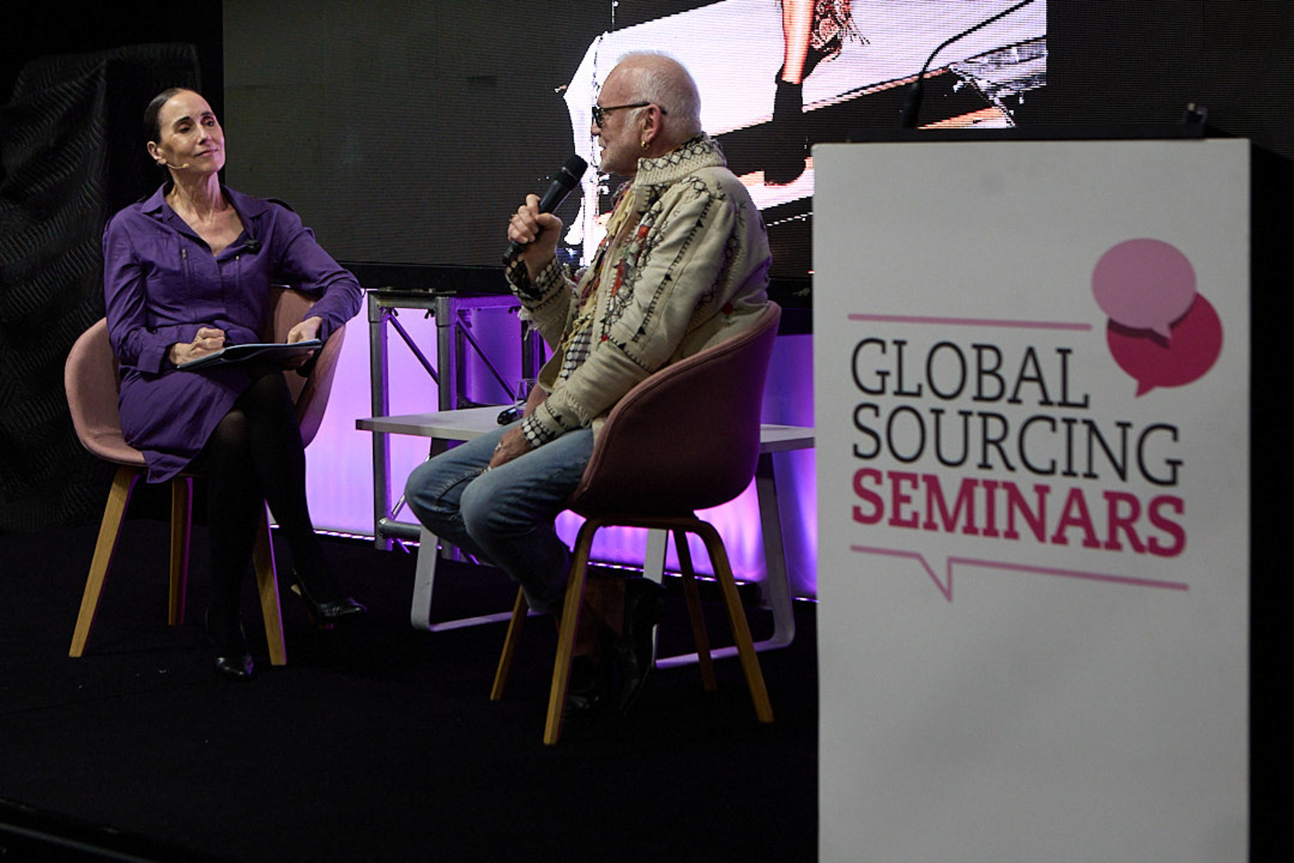 Side view of Nicholas Huxley and Patty Huntington in conversation on stage.