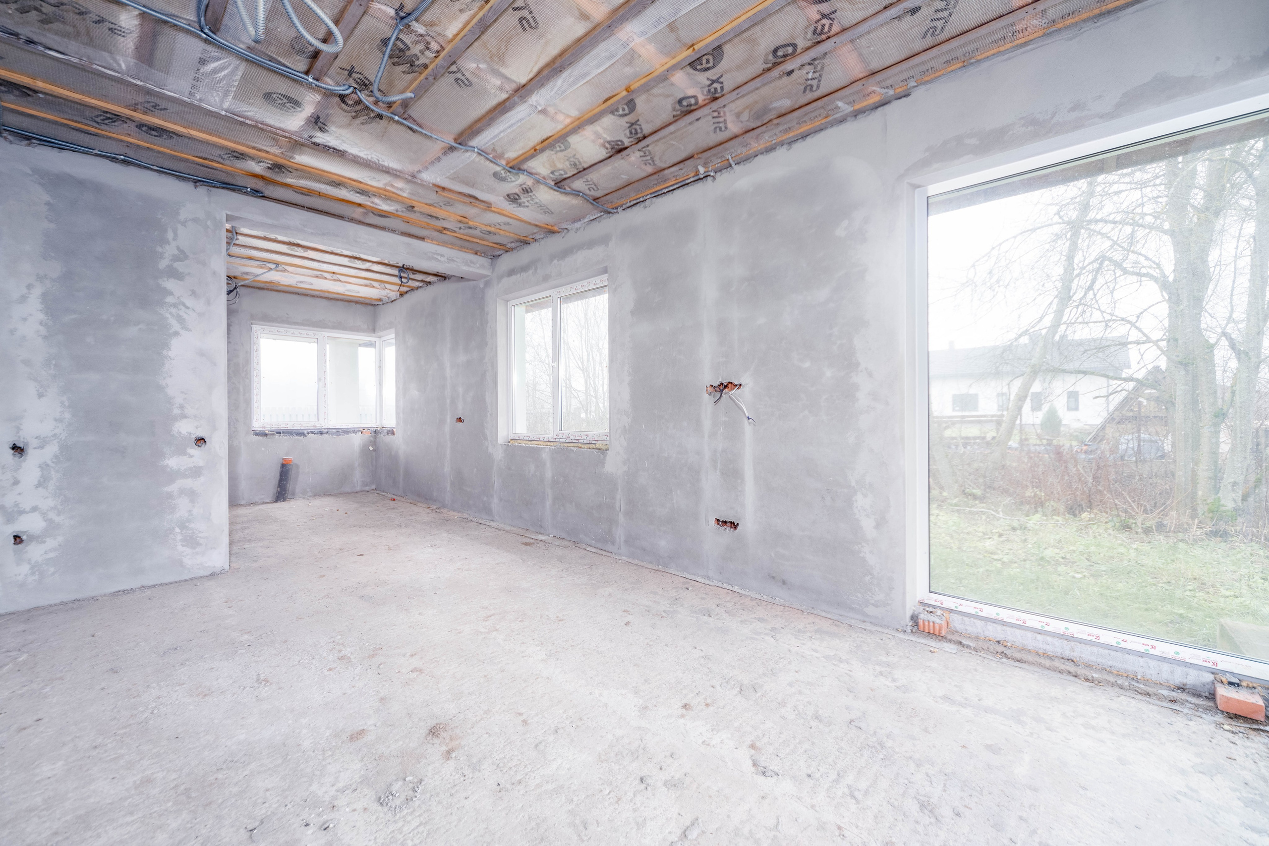 Интерьер кухни-гостиной с панорамным окном и видом в зону кухни в строящемся загородном доме